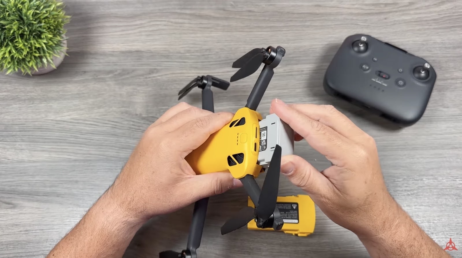 Hands unfold the yellow SkyRover X1 on a desk beside a gray controller.