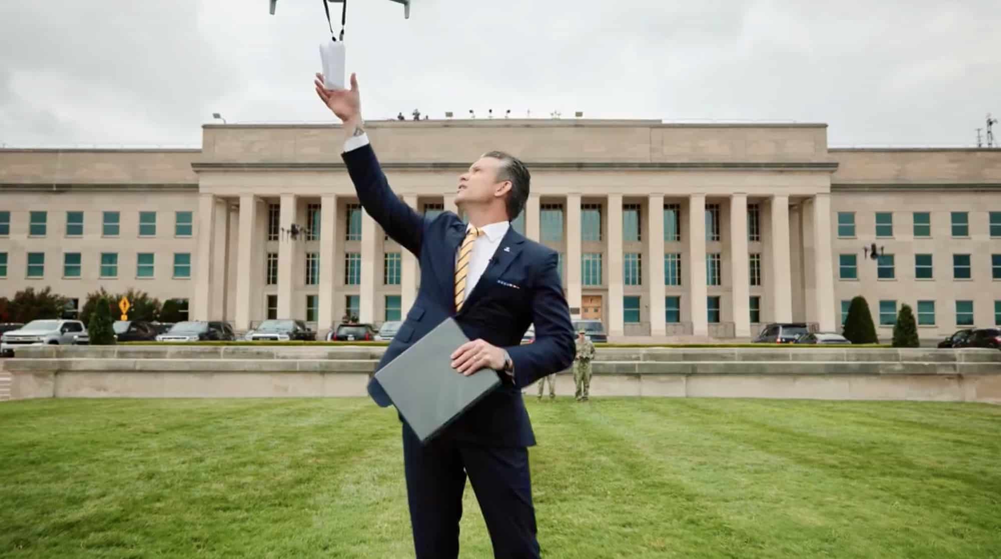 The defense secretary raises a hand to launch a small white drone outside the Pentagon.