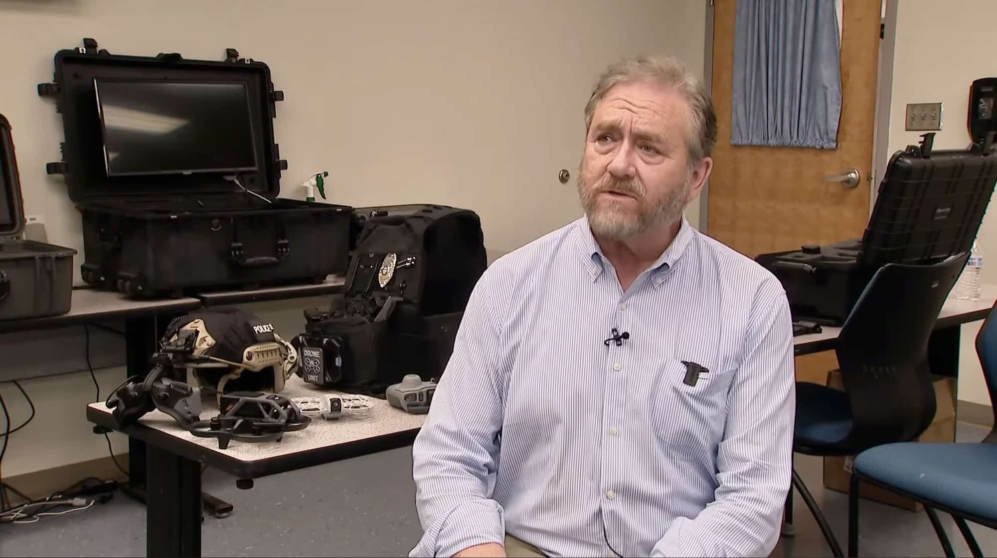An instructor speaks on camera beside hard cases of drone equipment.