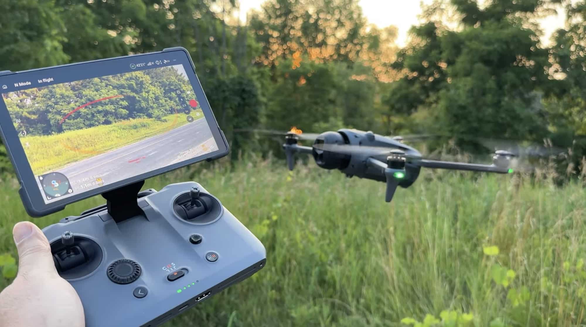 The controller in hand as the drone hovers over tall grass at dusk.