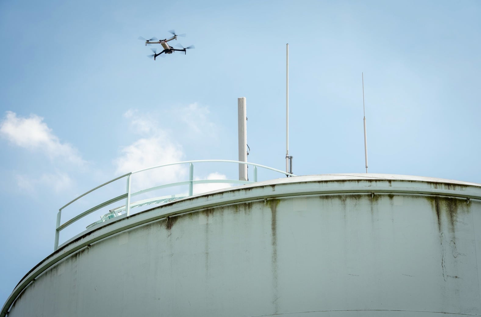 Quadcopter passes above a weathered municipal water storage tank.