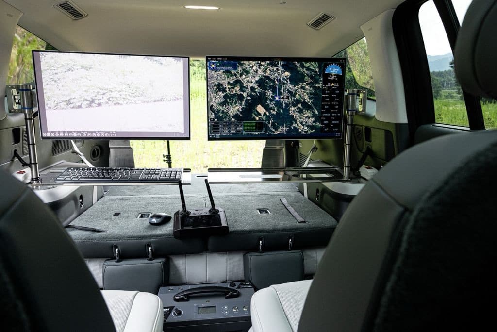 Vehicle interior converted into a control station with twin monitors and keyboard.