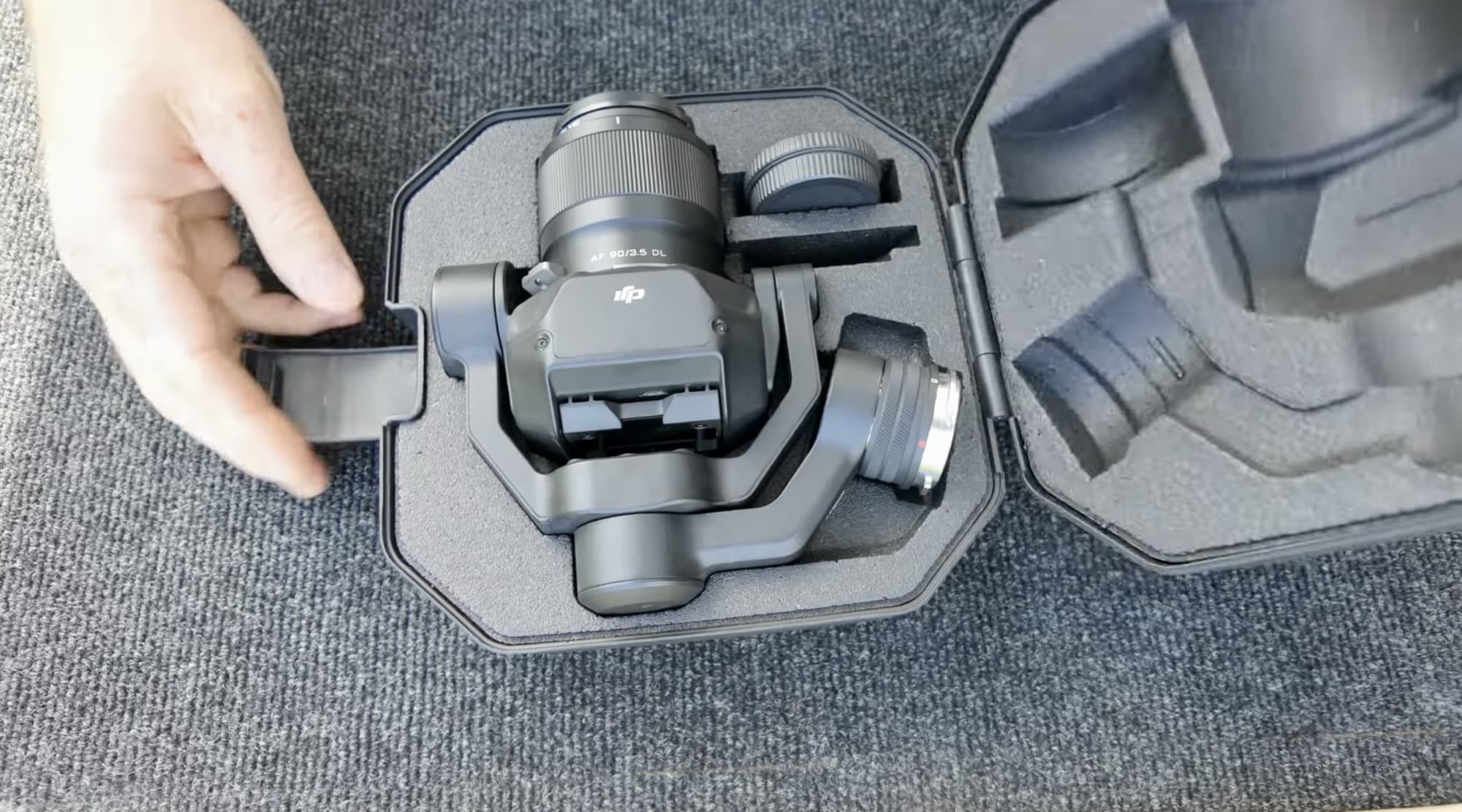 Hands setting the lens beside the Inspire 3 gimbal inside the padded case.