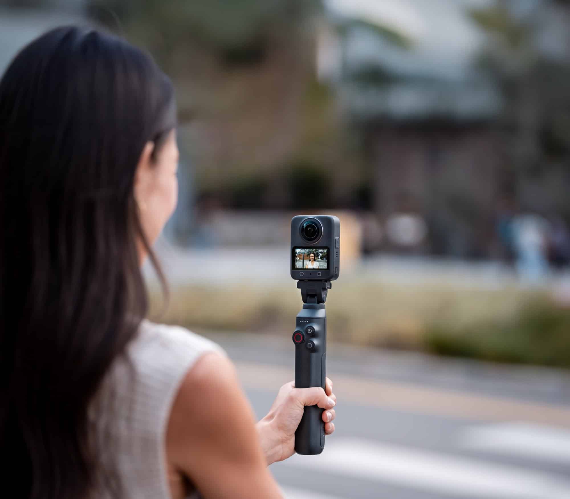 Over-the-shoulder view of the camera mounted on a battery extension rod on a street.