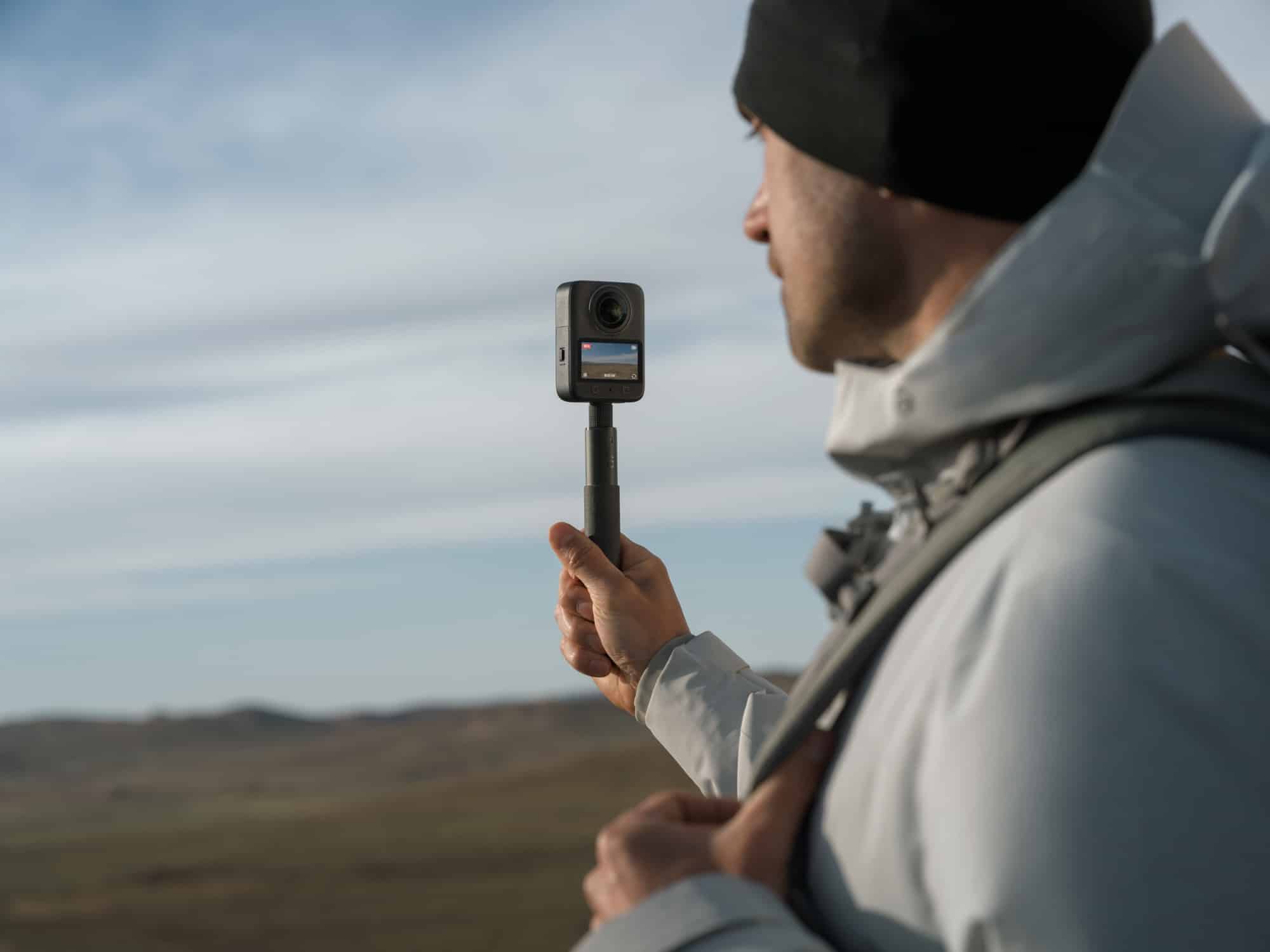 Profile of a hiker raising the camera on a short invisible selfie stick.
