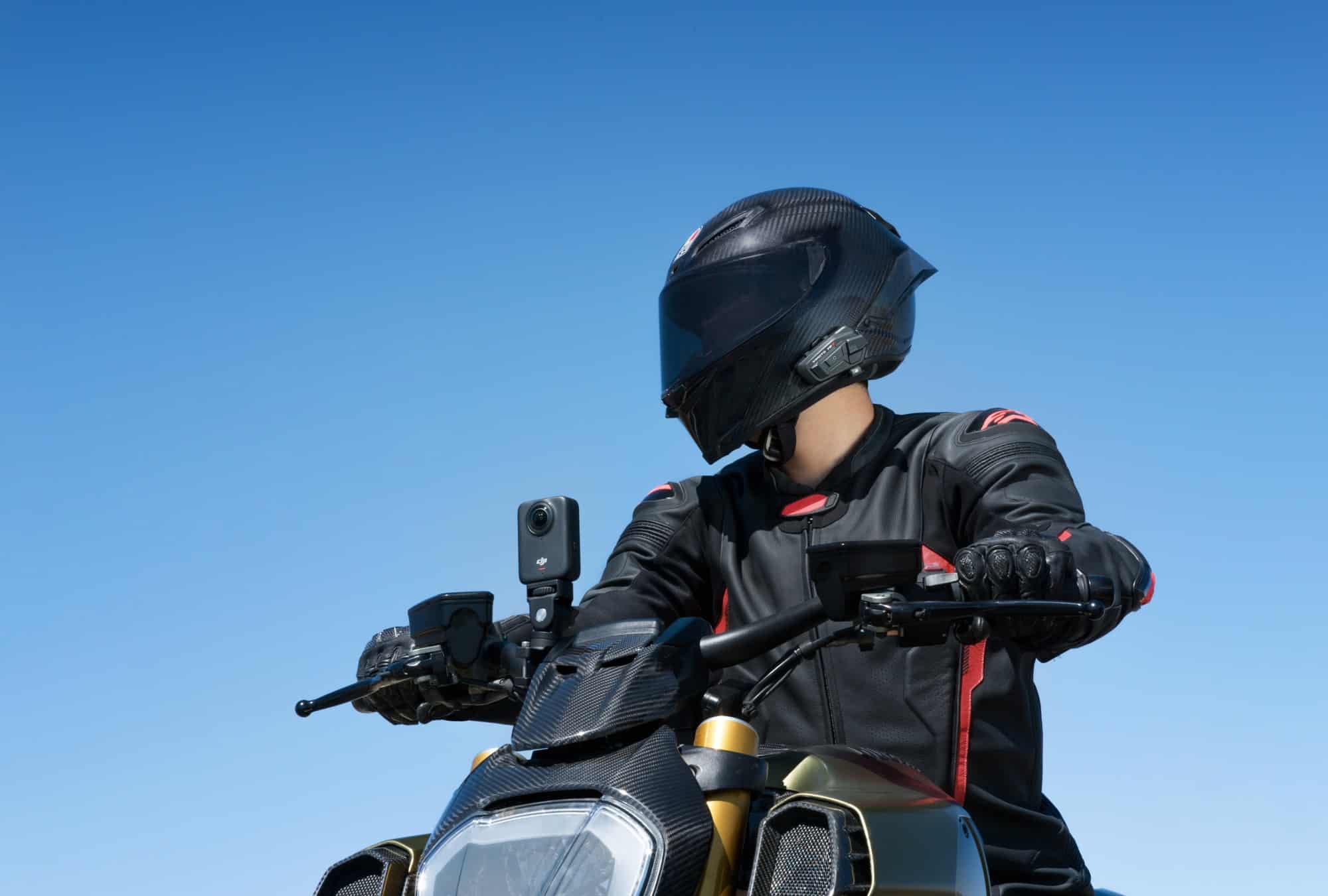 A rider grips the handlebars with the camera on a bar mount and a helmet headset.