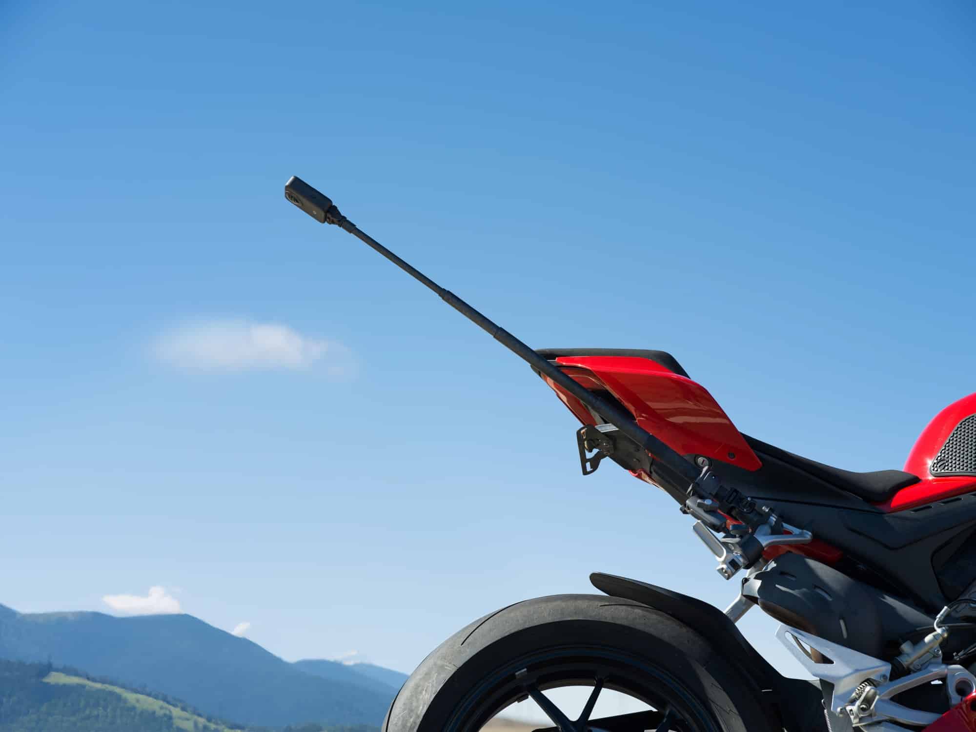A carbon fiber invisible selfie stick arcs off the tail of a red sportbike.