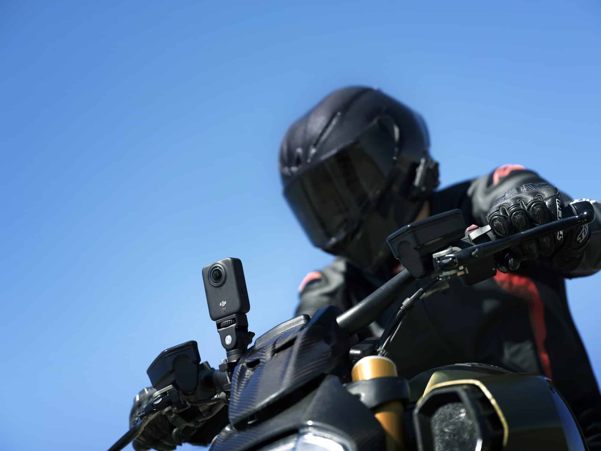 A motorcyclist in black leathers rides with the camera clamped to the bike.