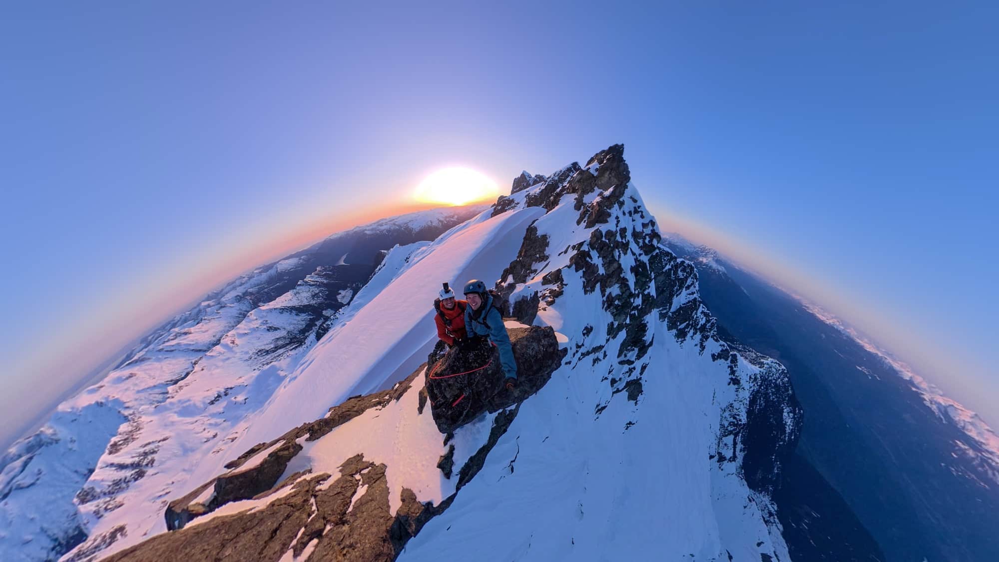 Tiny-planet 360 frame of a climber on a sunlit ridge curved into a sphere.