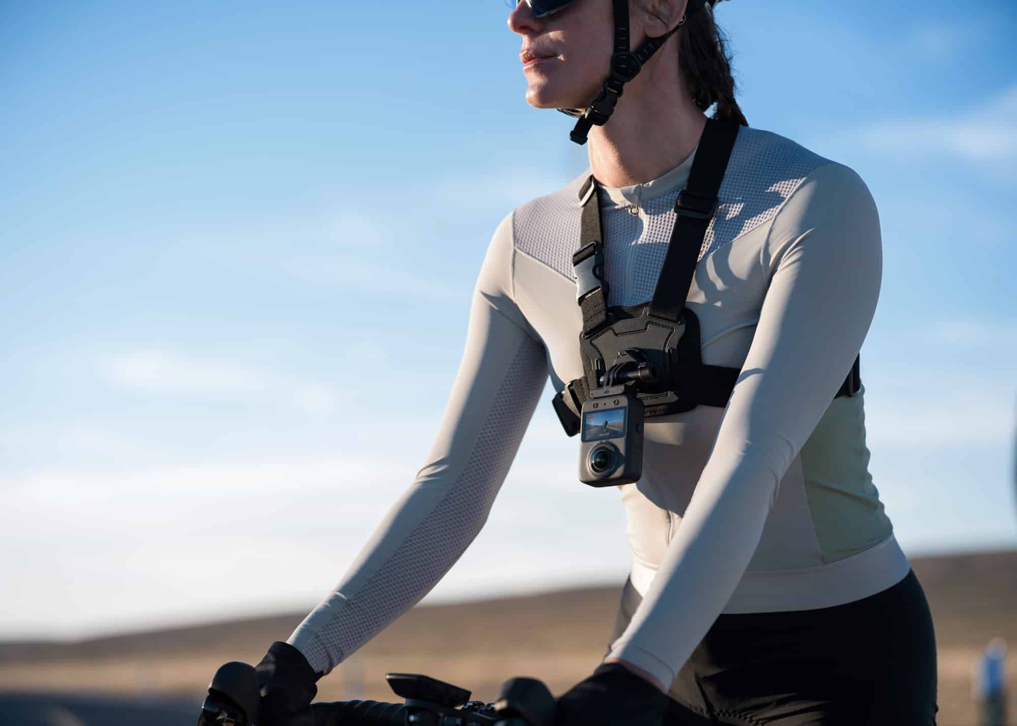 A cyclist rides with the 360 camera clipped to a chest strap harness.