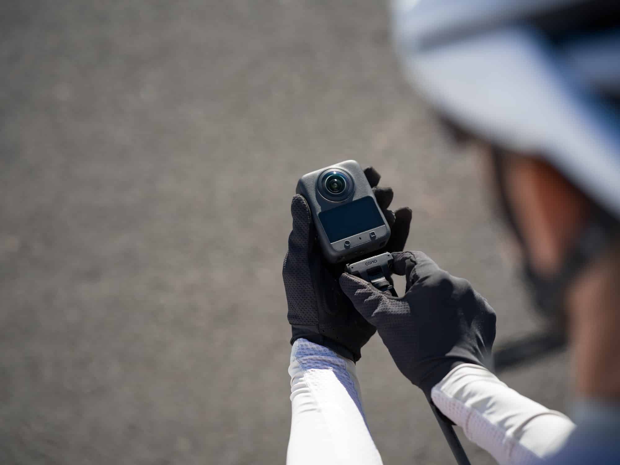 Gloved hands click the camera into a quick-release adapter mount.