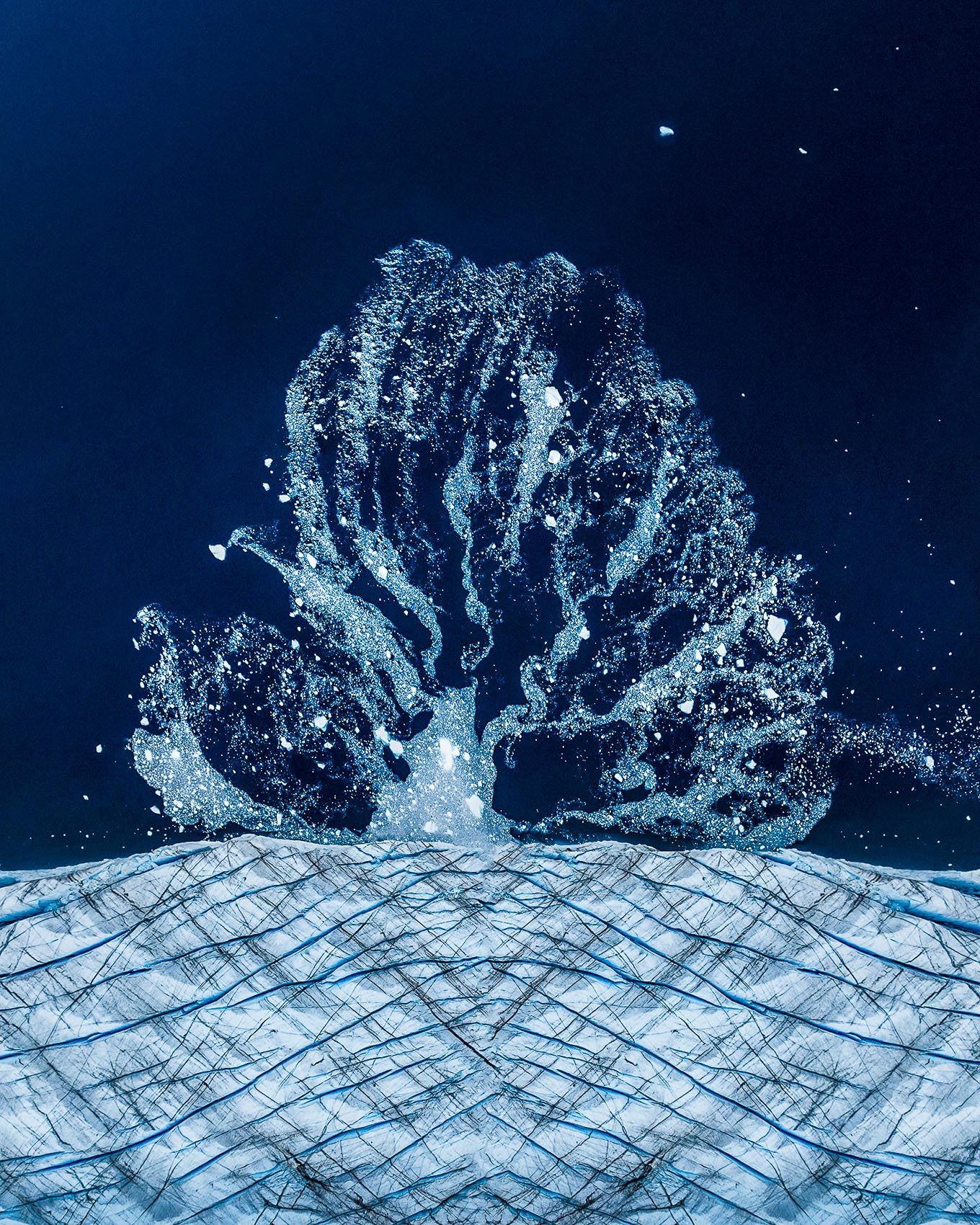 Overhead of blue meltwater channels branching like a tree across ice.