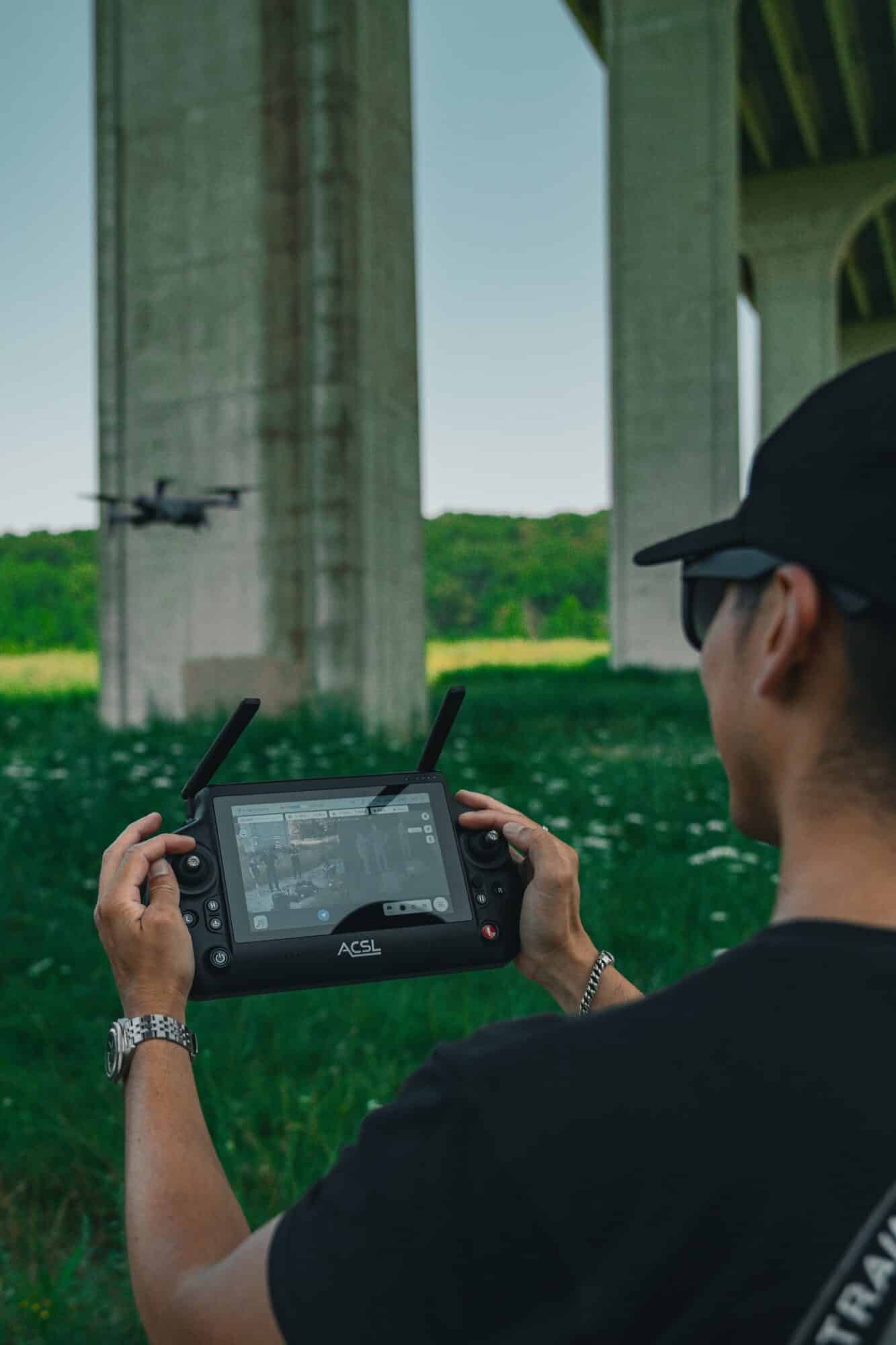 Pilot flying under a concrete viaduct using the ACSL TAITEN smart controller.