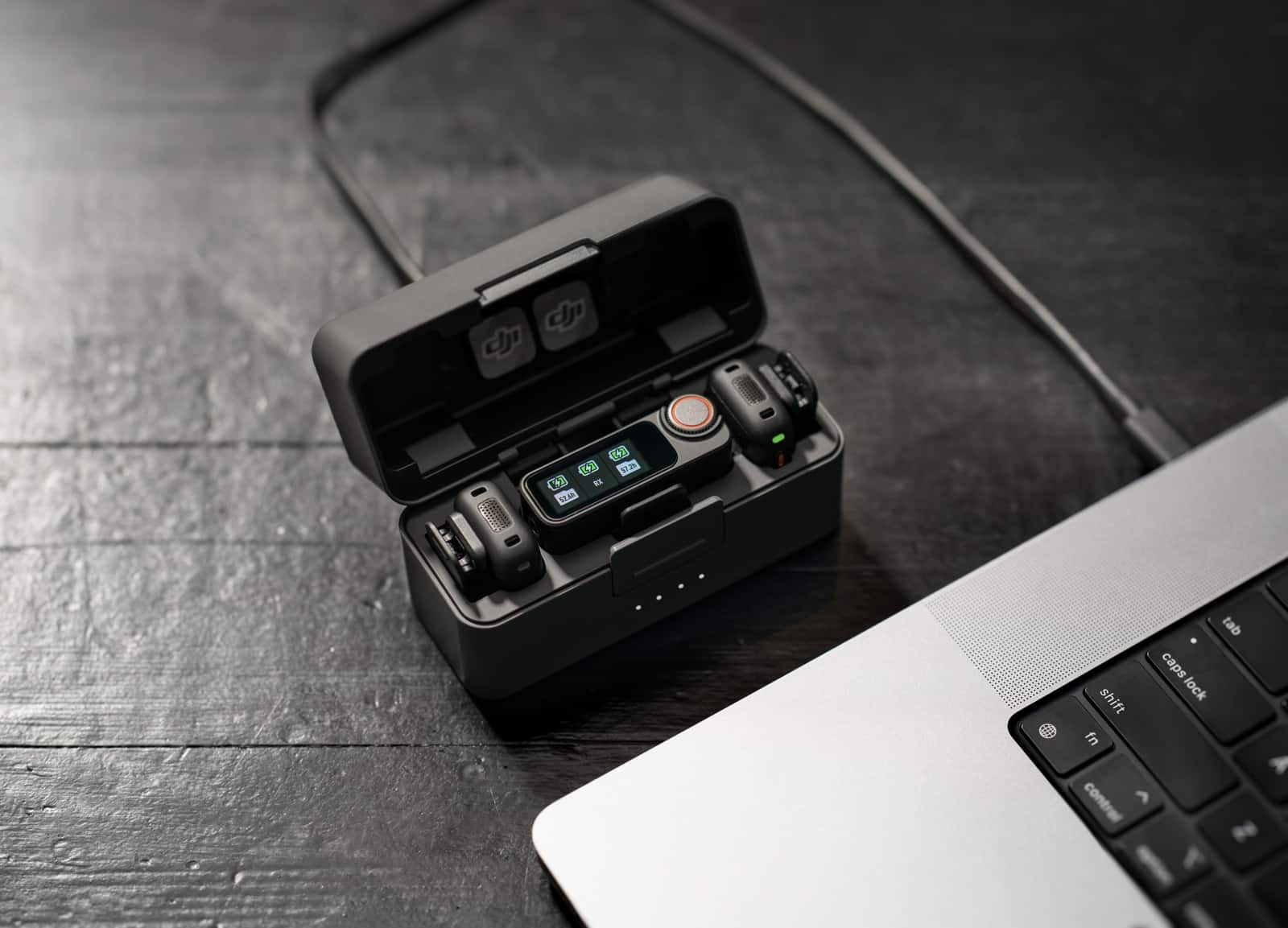 Open charging case on slate cabled into a laptop for file transfer.