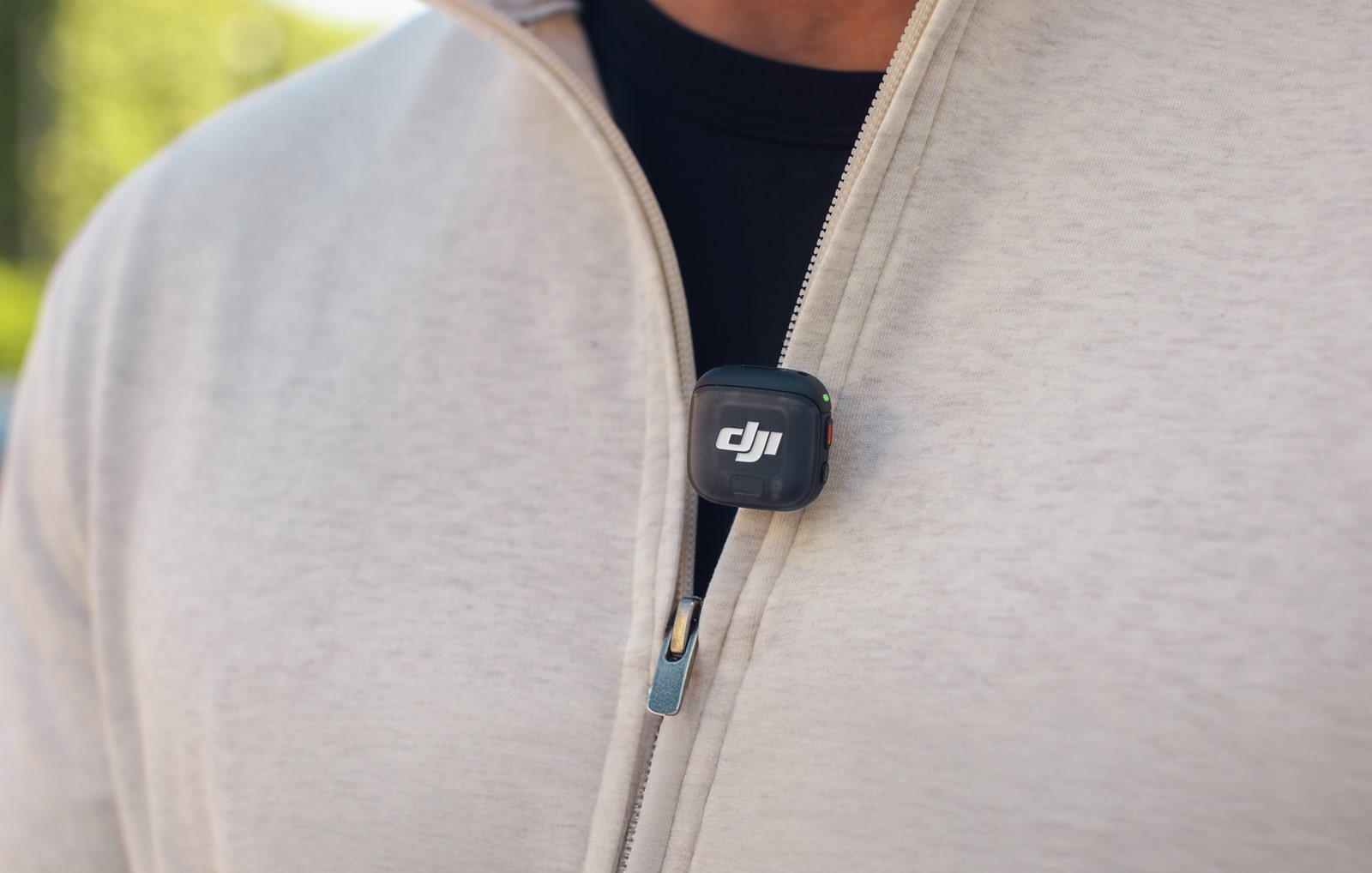 Transmitter clipped to the zipper placket of a cream fleece jacket.