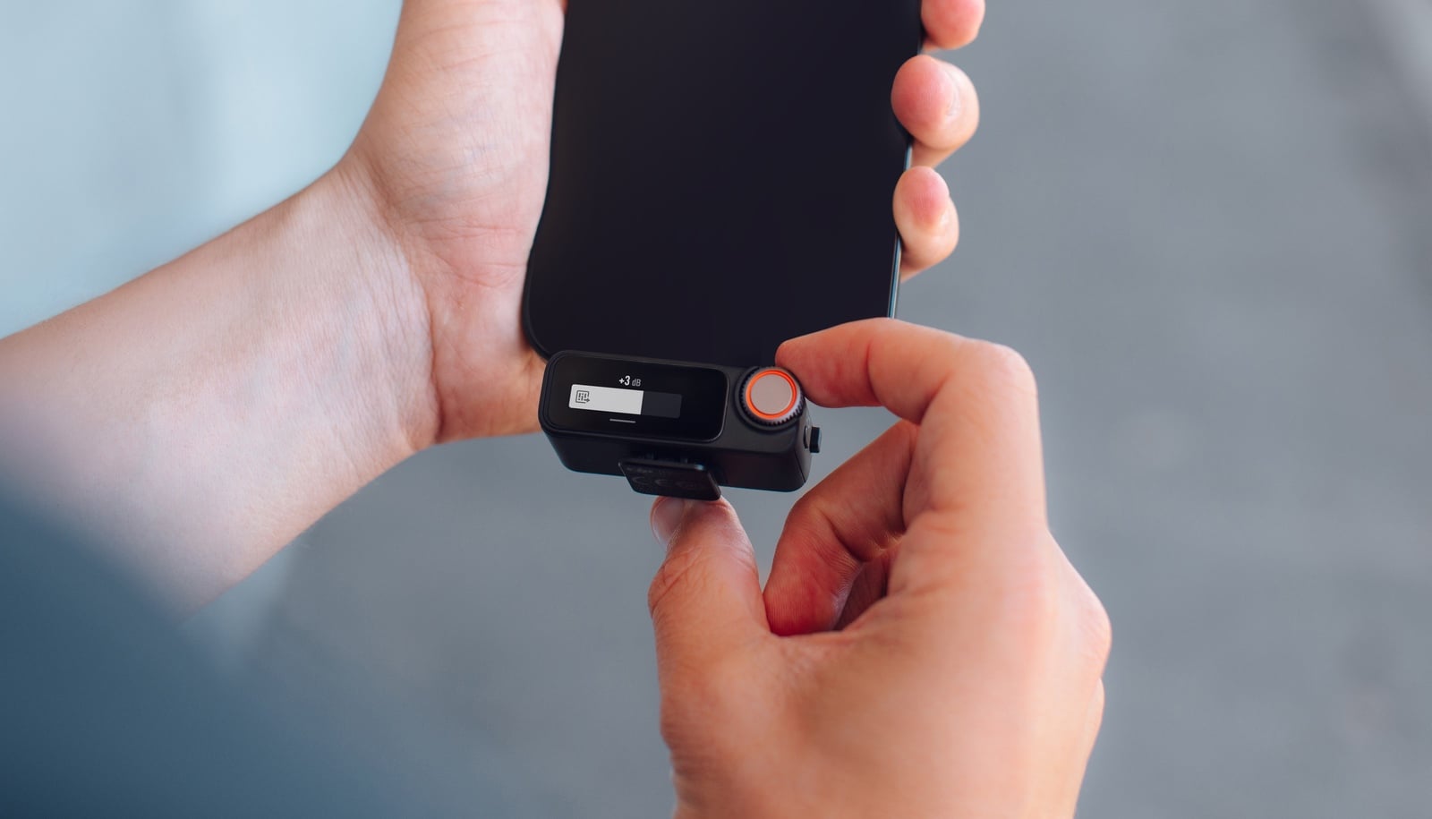 Fingers press the receiver onto the back of a smartphone.