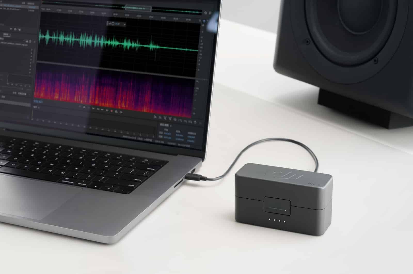Audio waveform and spectrogram on a laptop beside a studio monitor and case.