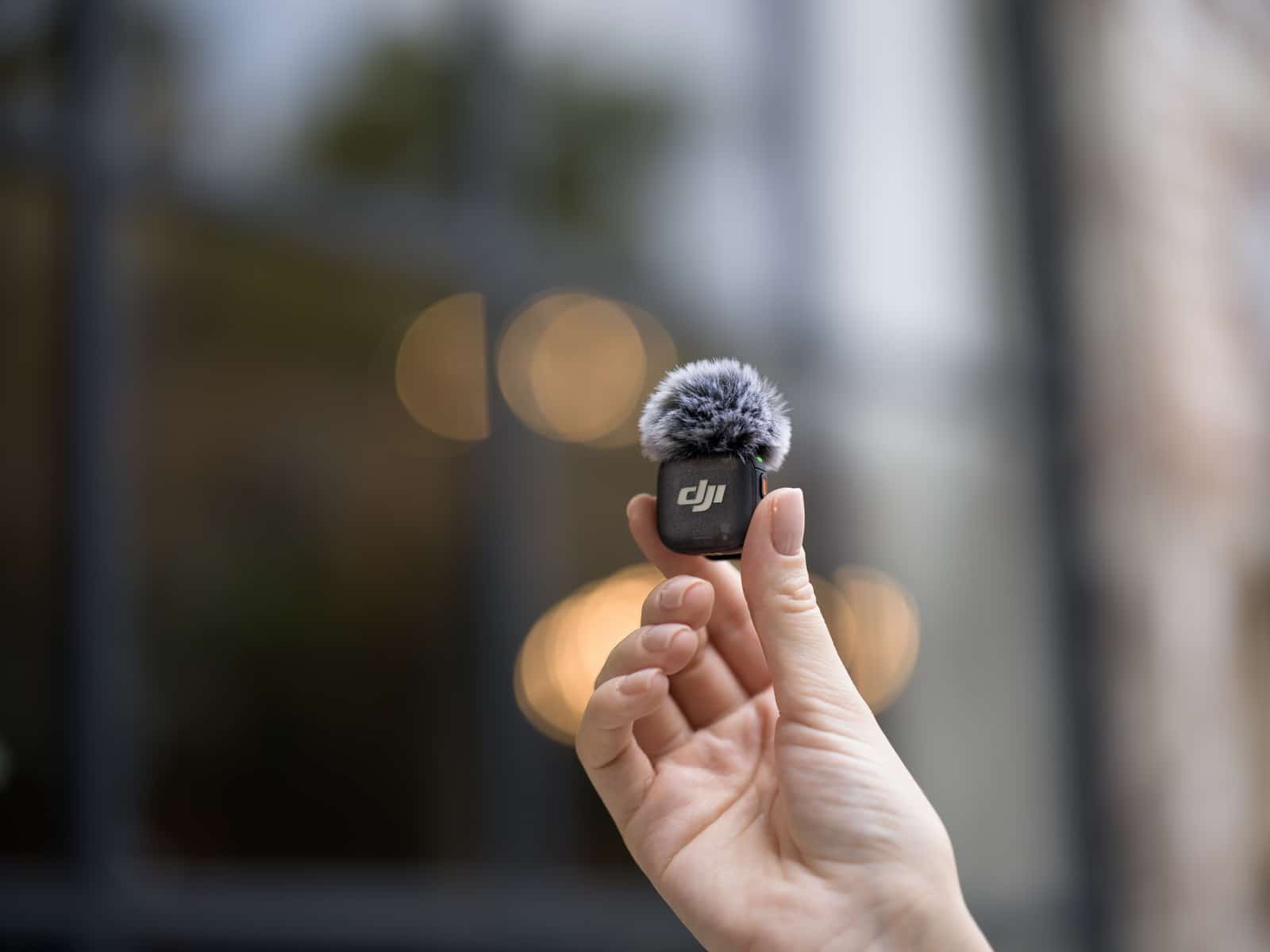 Transmitter with a gray windscreen held up against blurred city bokeh.