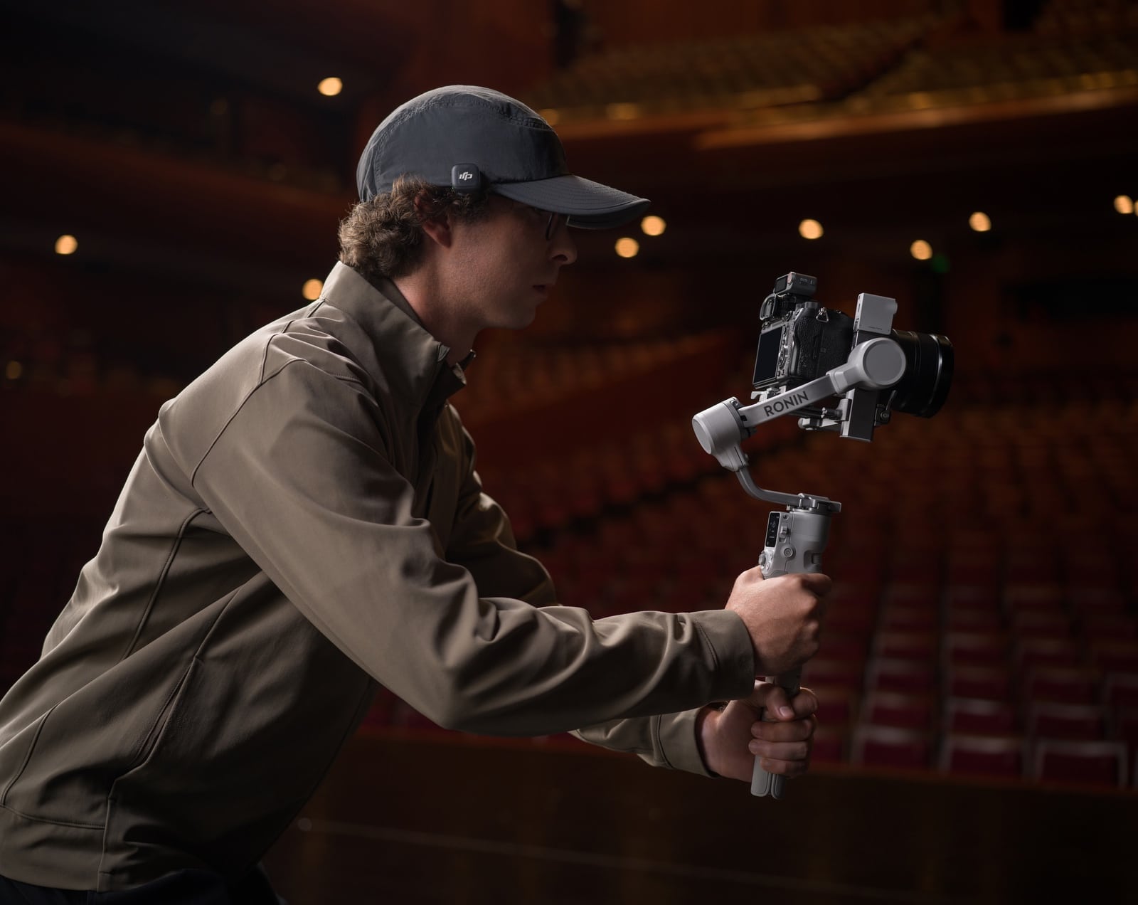 Camera operator wears a transmitter clipped to his cap brim while filming.