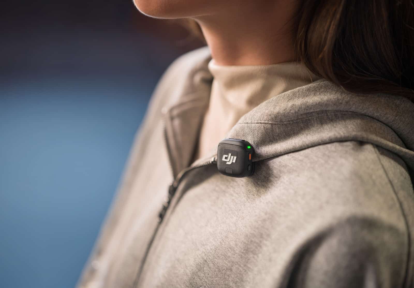 Transmitter worn upside down on a beige lapel with its green light showing.