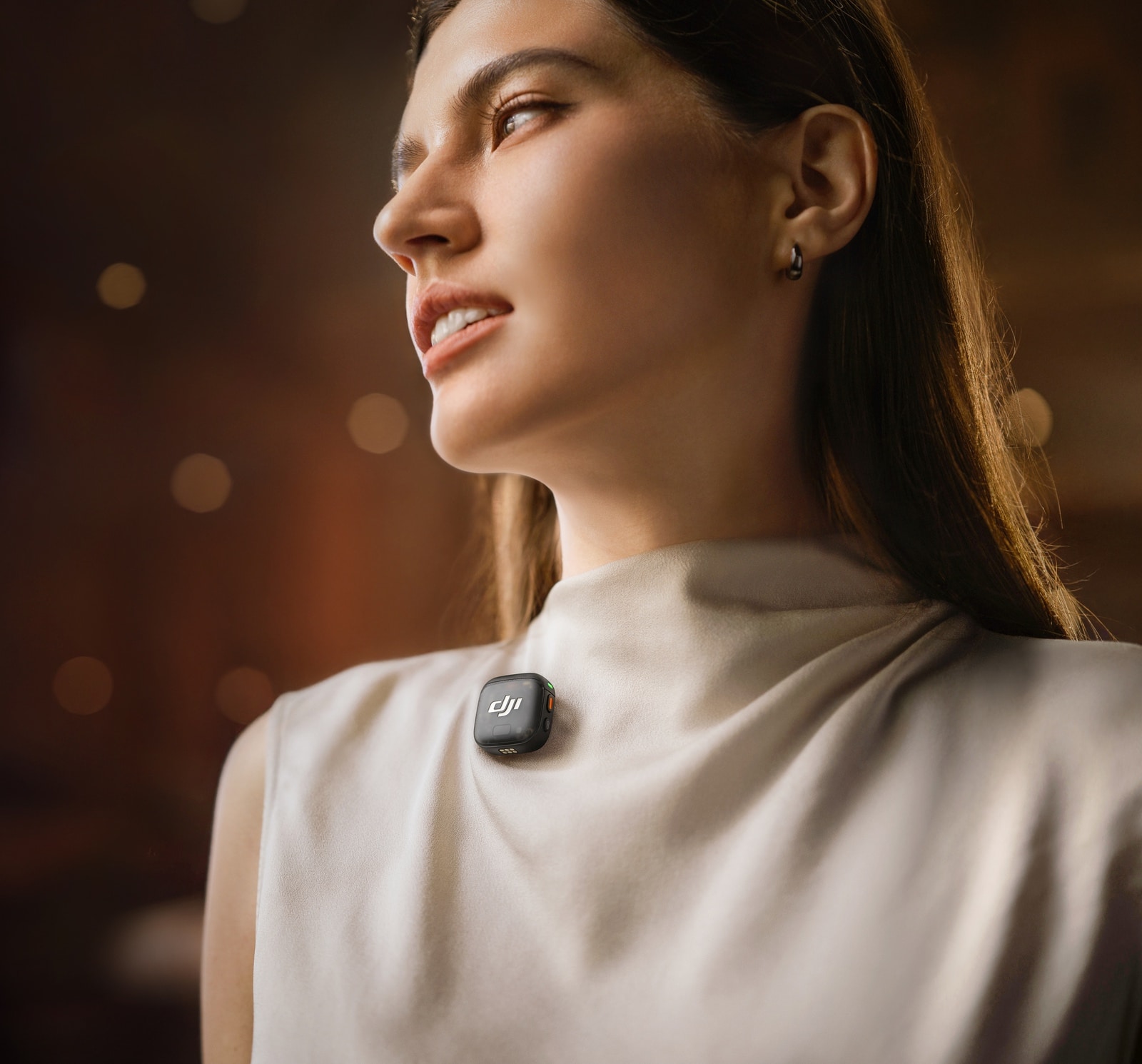 Profile of a woman in cream with a transmitter clipped near her collar.