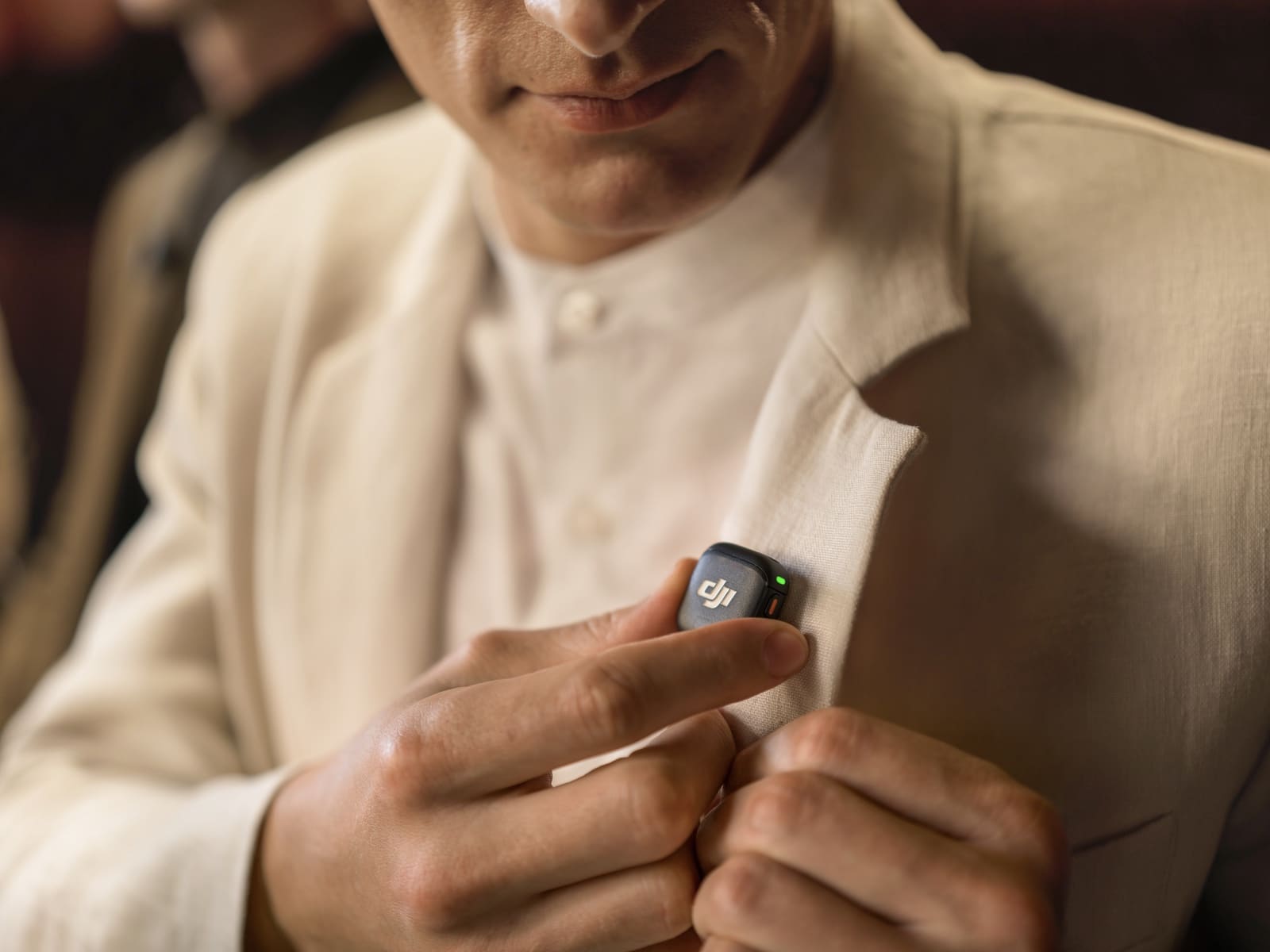Man in a cream shirt fixes a magnetic transmitter to his sleeve.