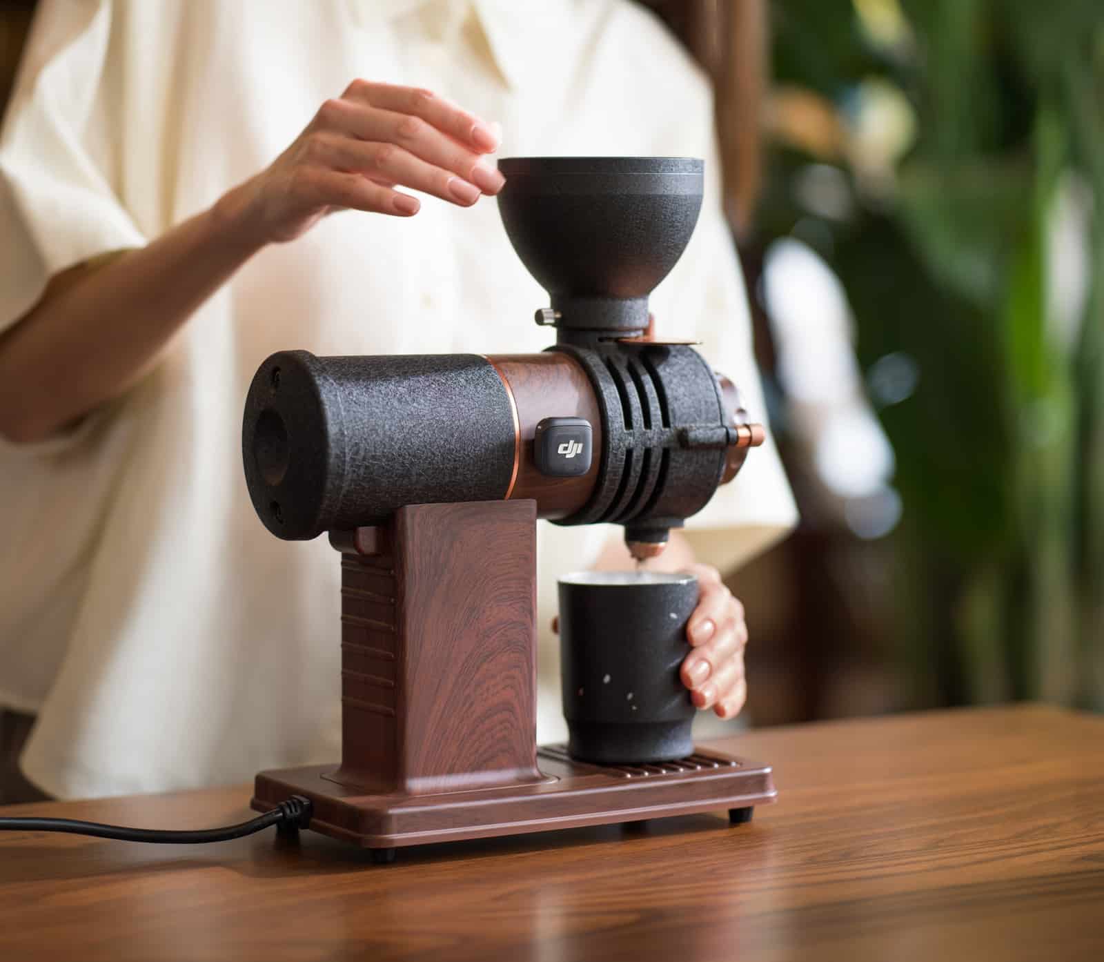 Transmitter magnet-mounted on a coffee grinder as a hand loads the hopper.