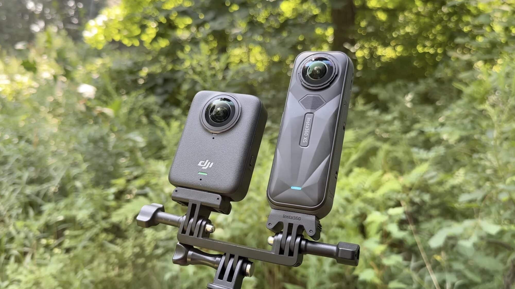 Both cameras clamped side by side on a mount in front of green foliage.