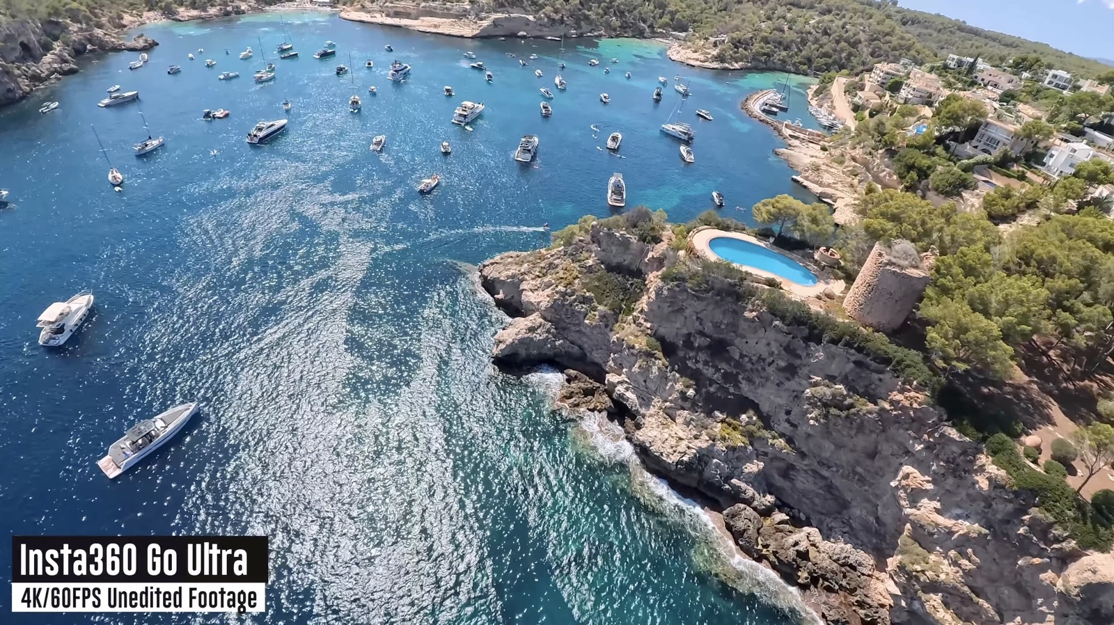 Aerial sample frame over a boat-filled Mediterranean cove, shot at 4K 60fps.