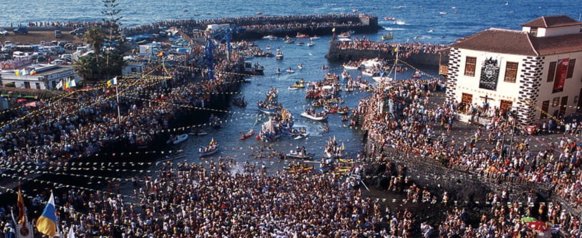 Aerial view of a packed harbour festival with boats and crowds along the seafront.
