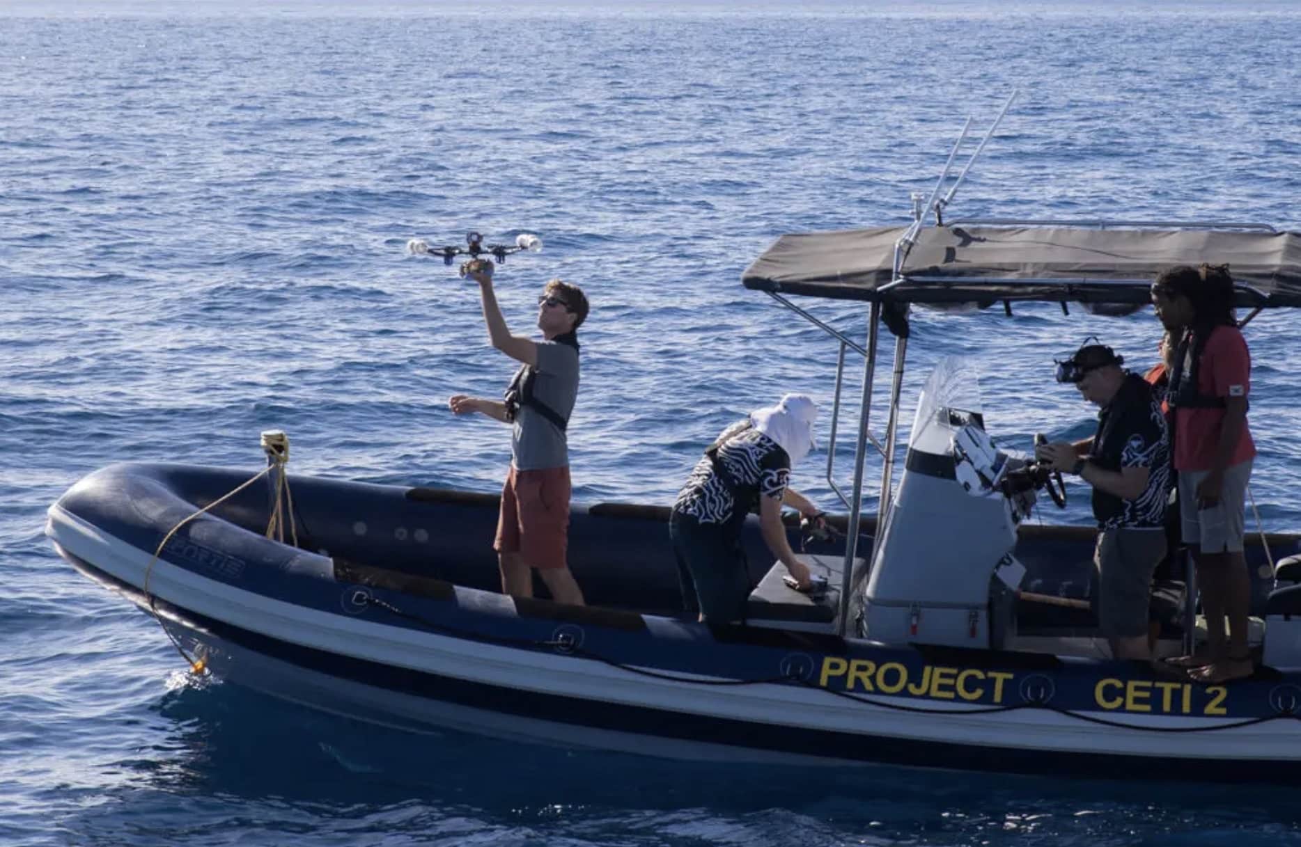 Researchers on a Project CETI inflatable boat launch a drone over open sea.