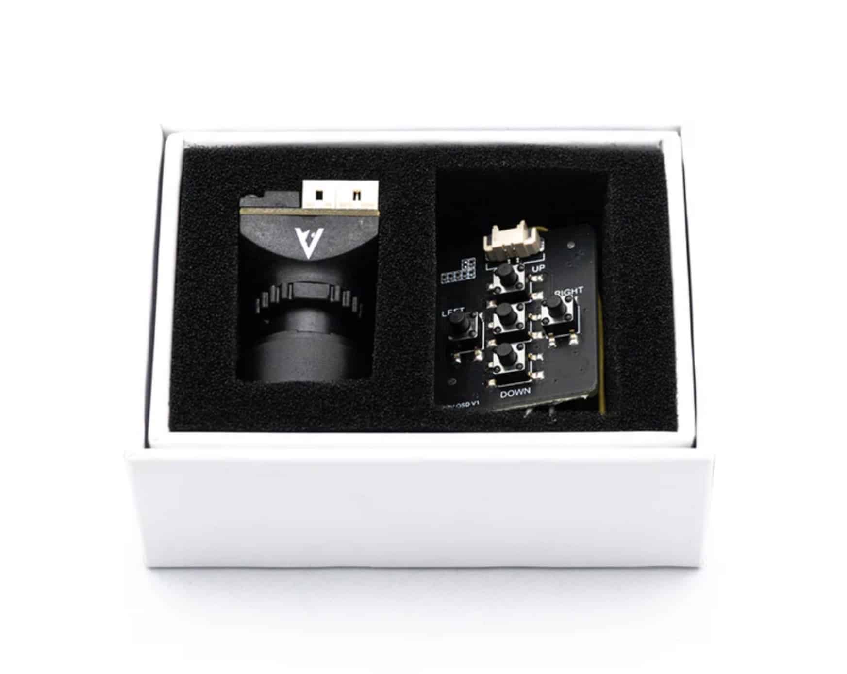 An FPV camera and circuit board sit in foam cutouts inside a white product box.