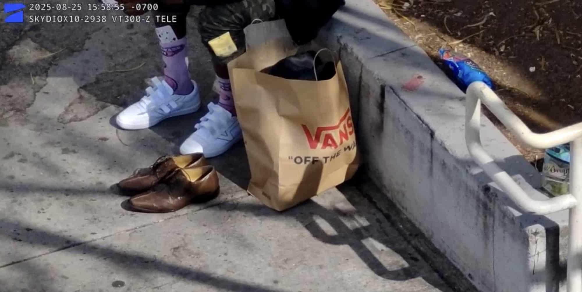 Zoomed drone footage of new white sneakers next to discarded shoes and a Vans bag.