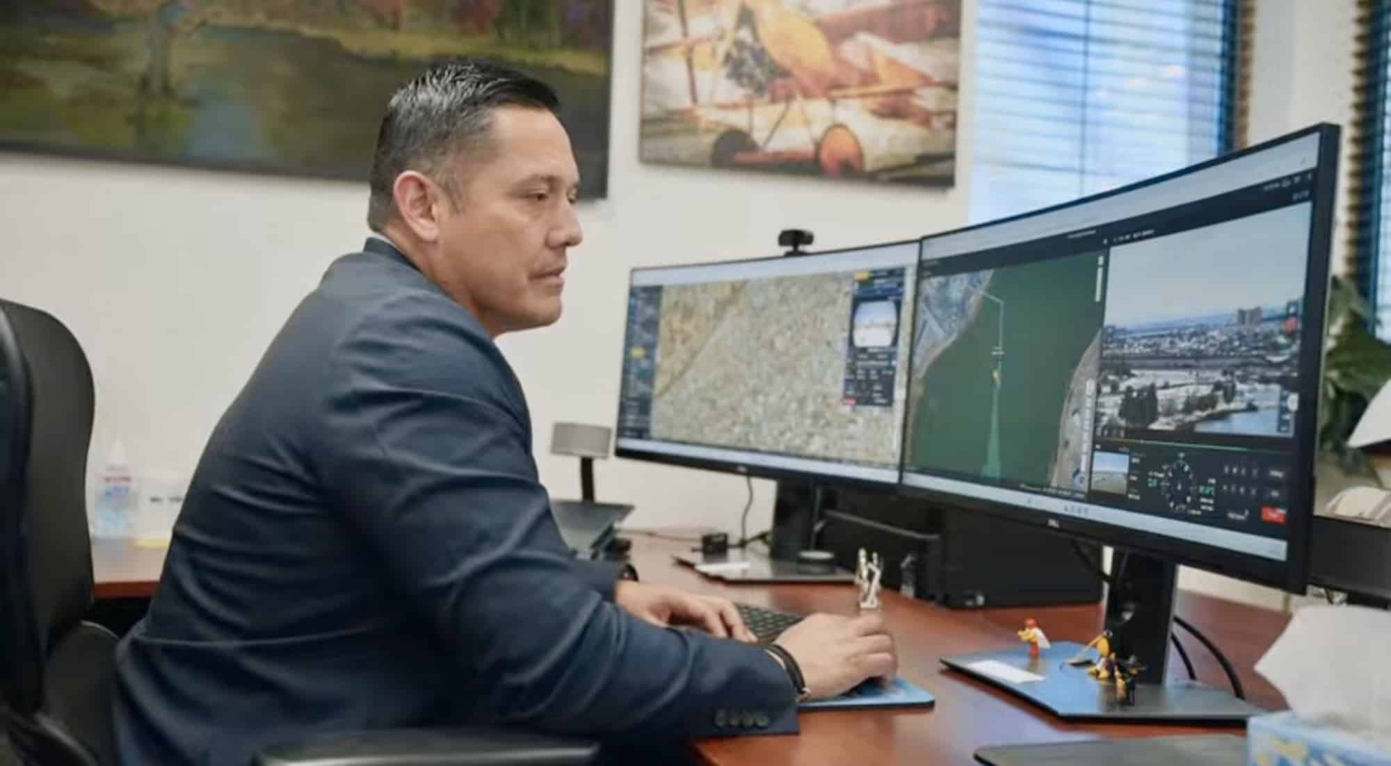 Program leader at a curved monitor showing a live map and drone camera feed.