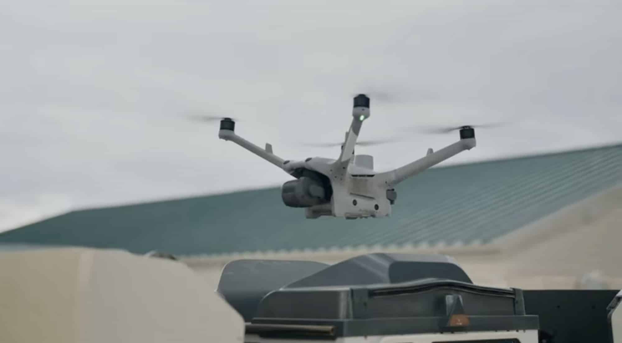 Drone hovering above its dock on a green metal rooftop.