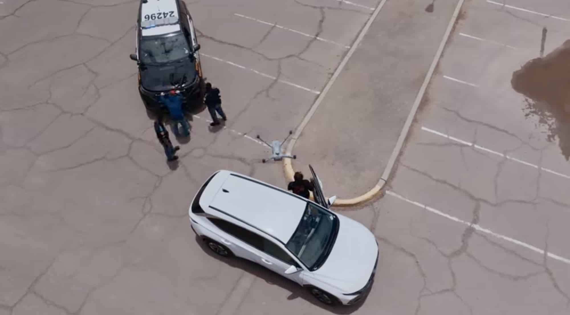 Aerial view of a police motorcycle and a white SUV stopped on cracked pavement.