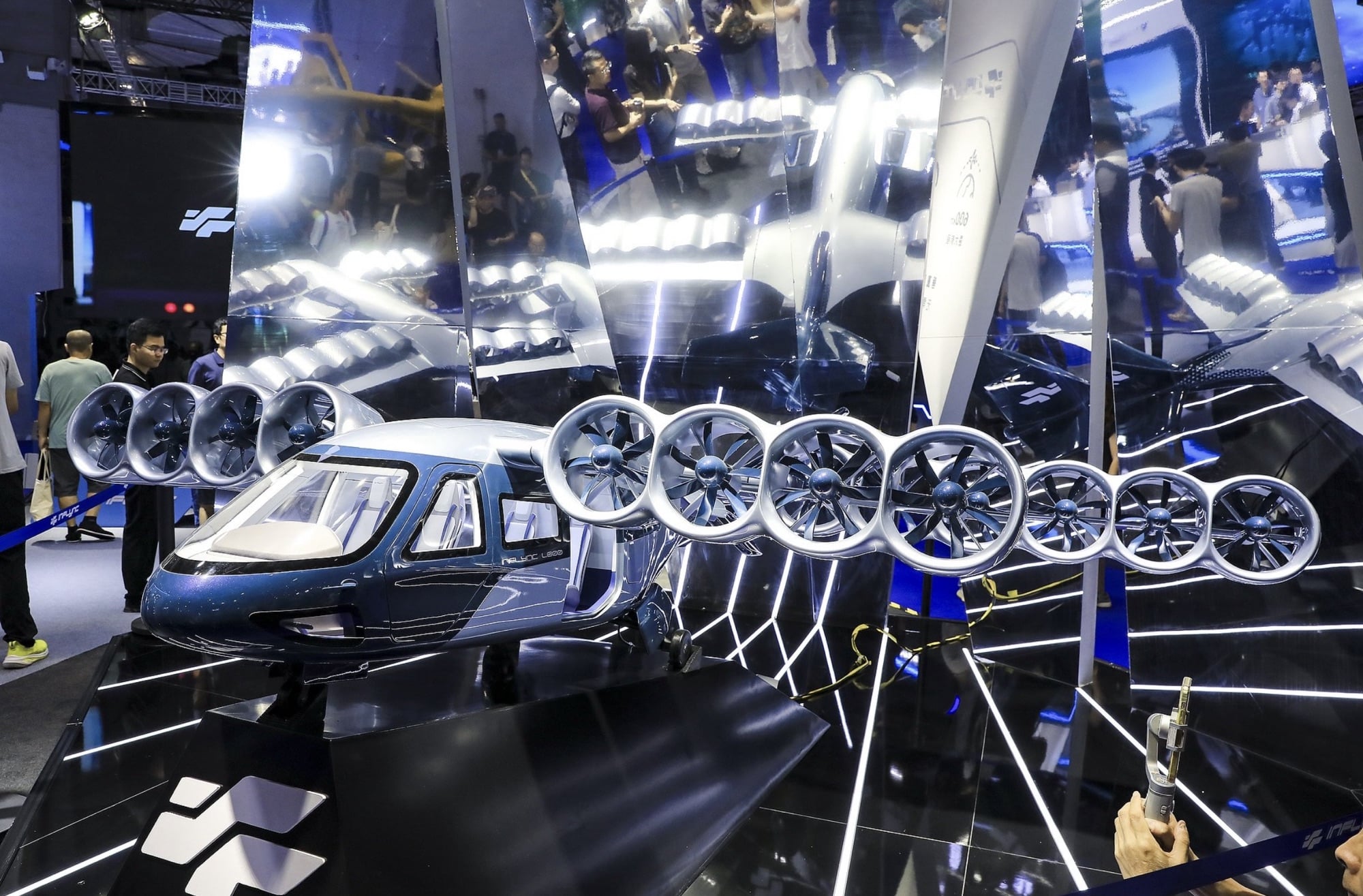 Ceiling mirror reflects an eight-rotor passenger aircraft on the show floor.