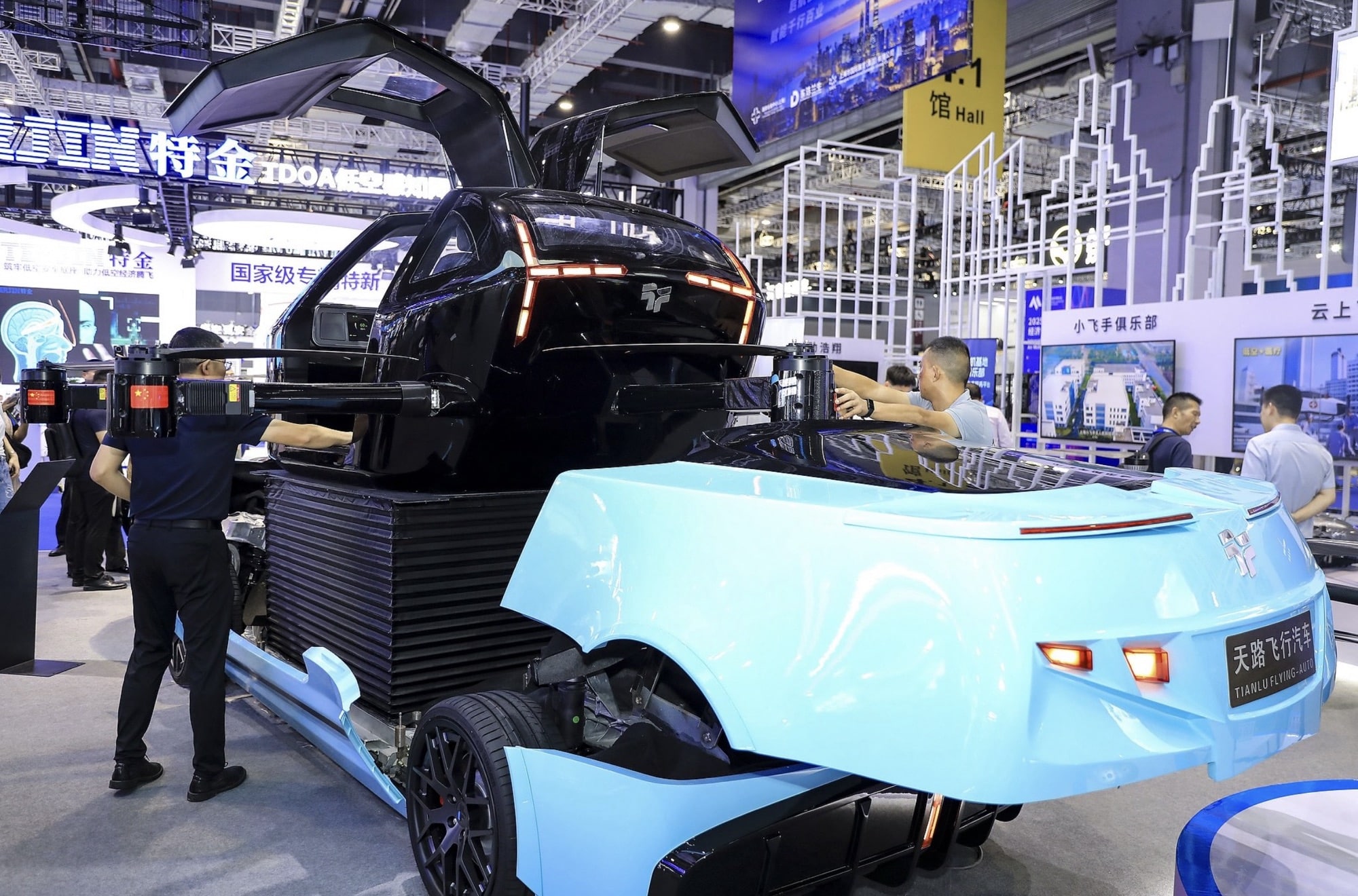 Pale blue road vehicle with a detachable flight module draws expo visitors.