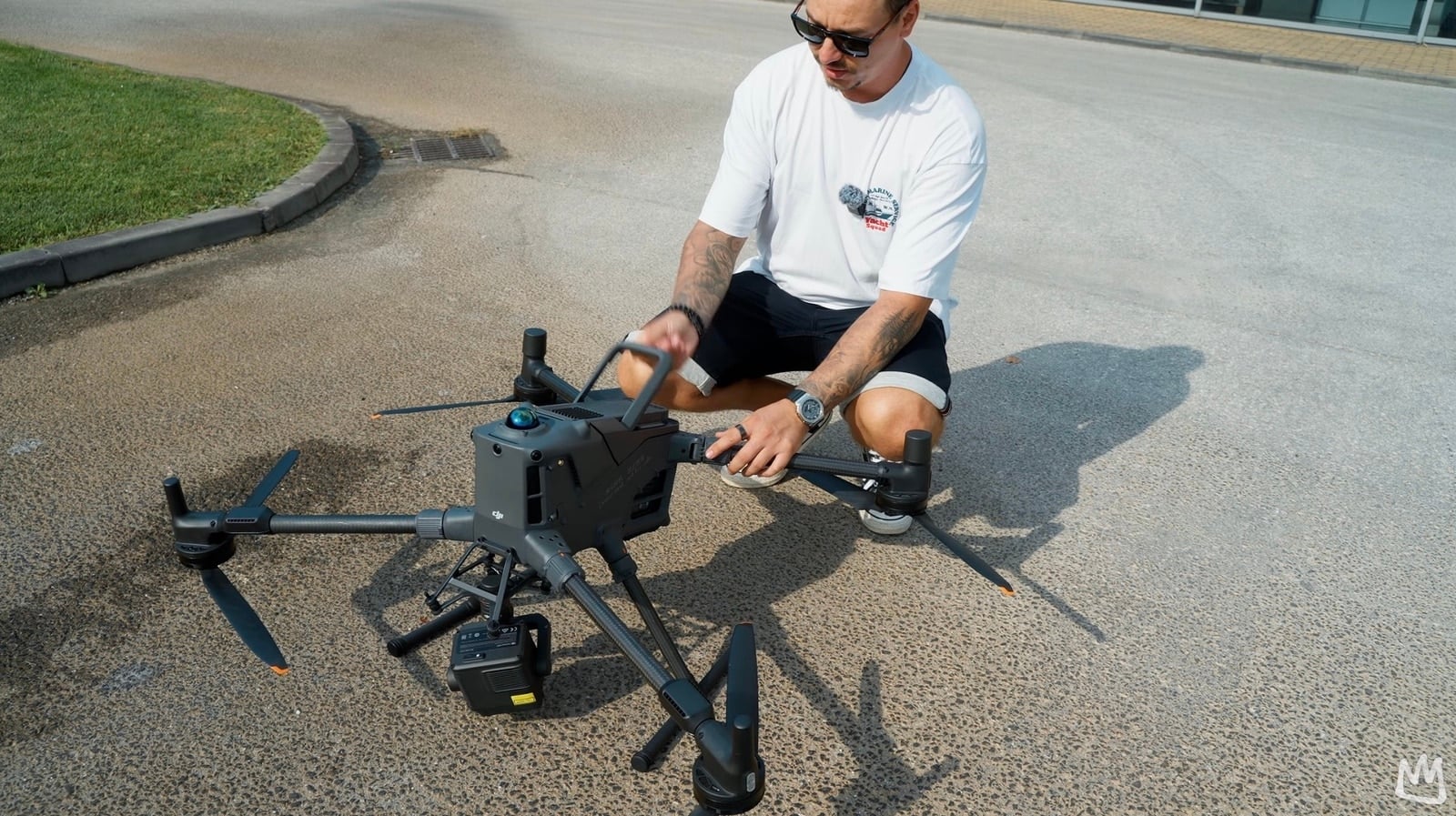 Man in sunglasses crouches beside the unfolded Matrice 400 on tarmac.