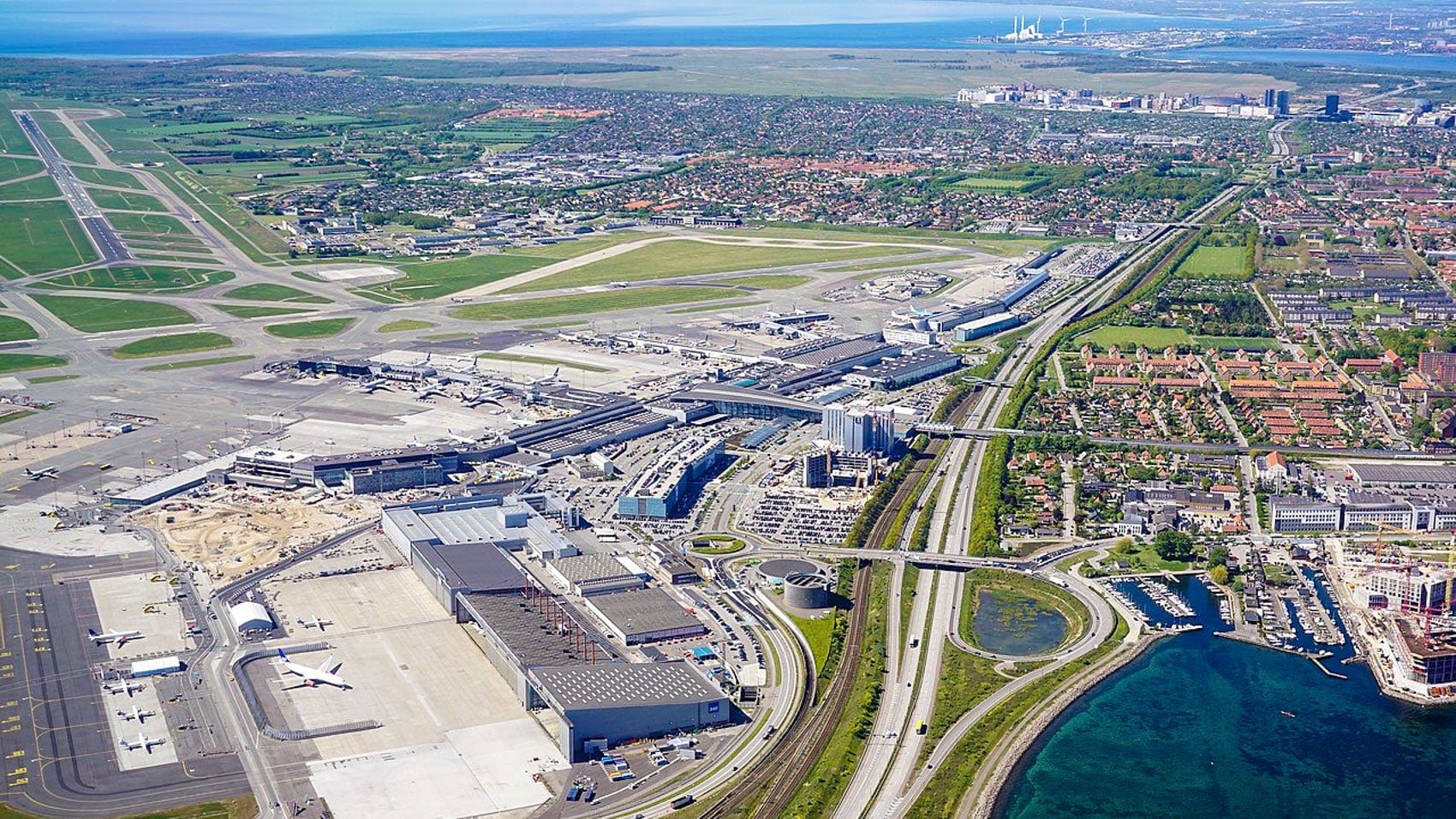 Aerial view of Copenhagen Airport runways and terminals beside the coastline.