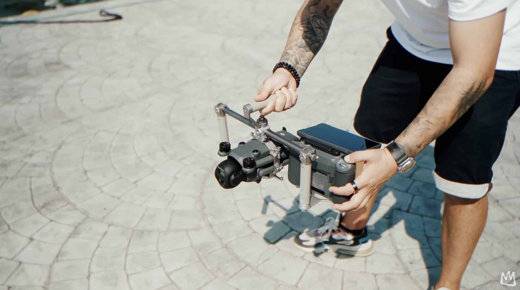 Man assembles the Tilta handle rig around a drone on a paved plaza.