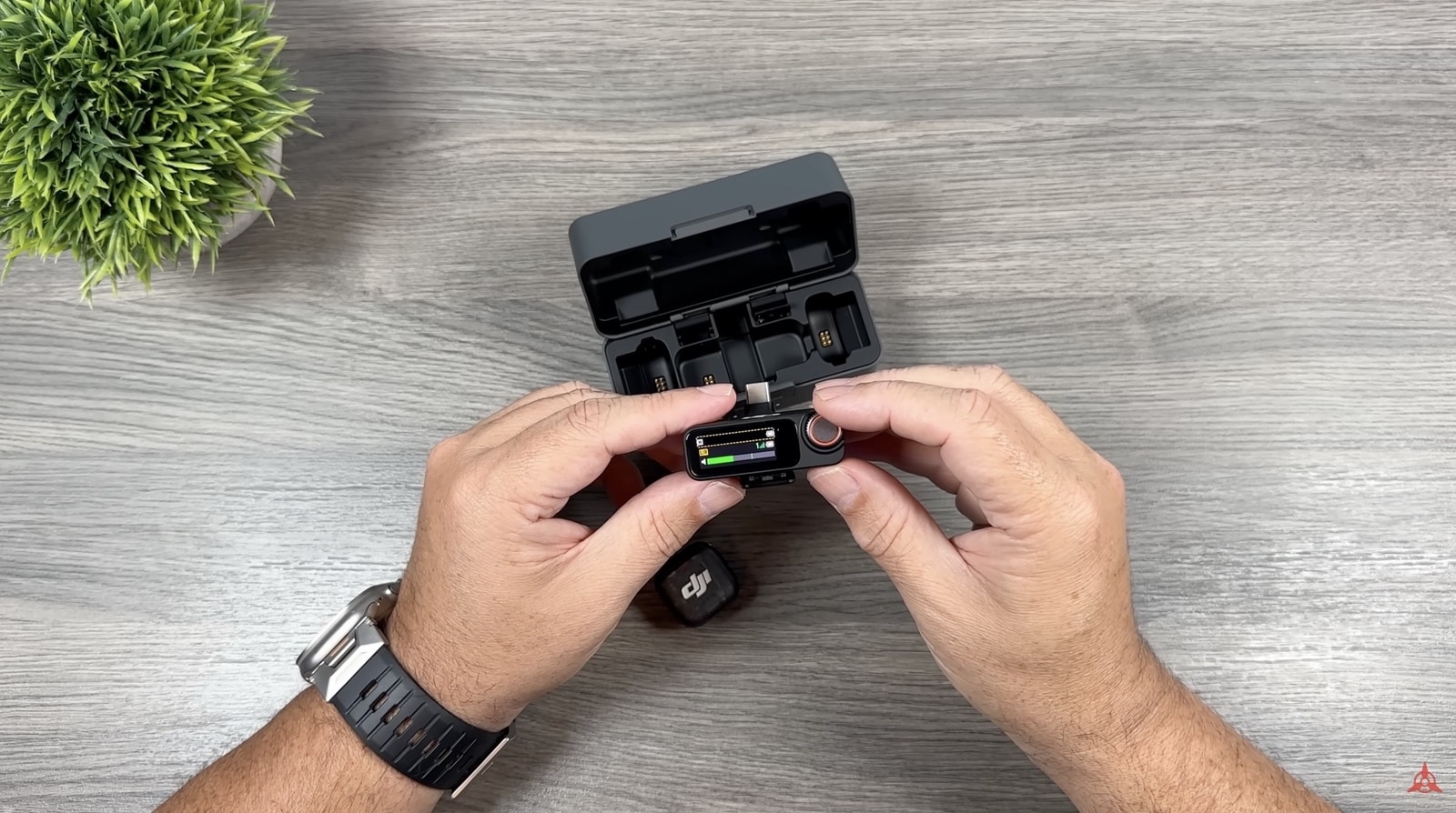 Hands lifting the receiver from the open case, one transmitter left on the desk.