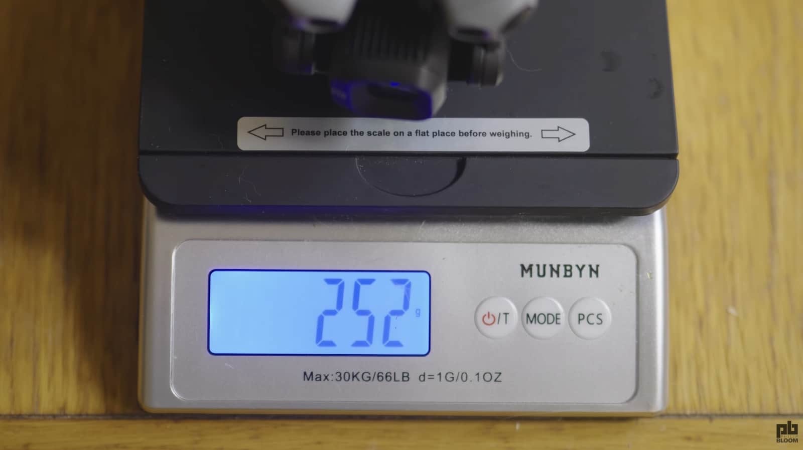 A drone rests on a MUNBYN digital scale reading 252 grams on a wooden desk.