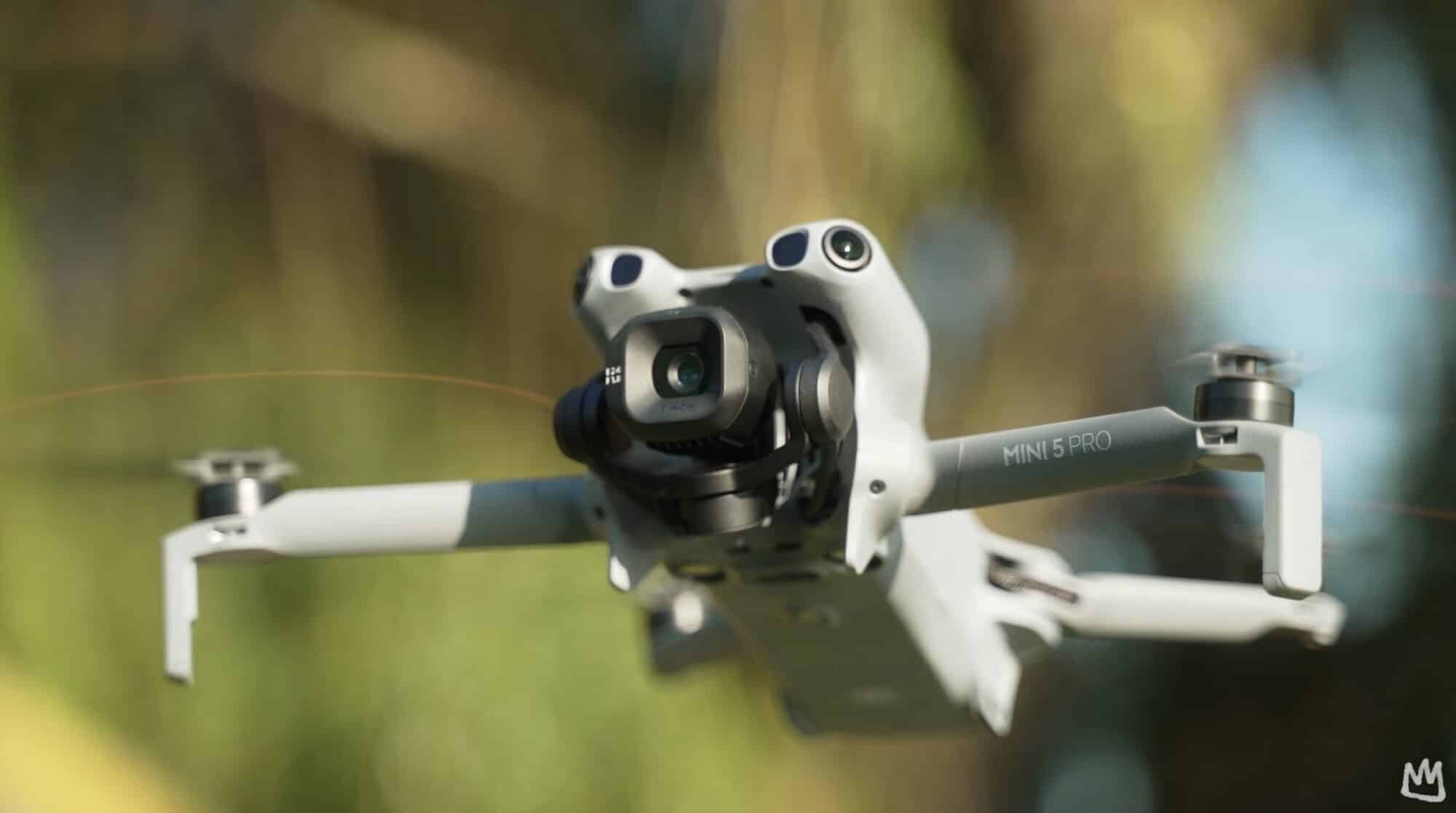 Mini 5 Pro hovering close to the lens against blurred autumn foliage.