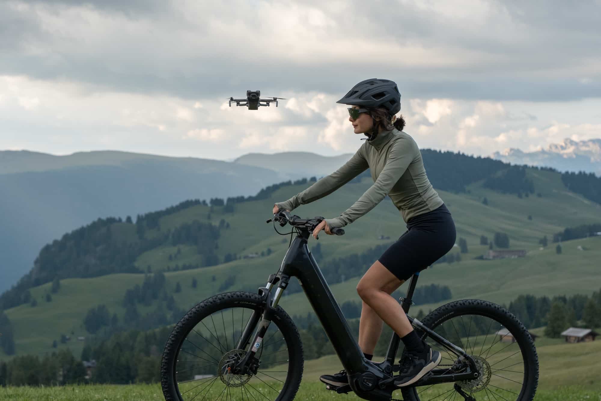 Side view of the drone tracking a cyclist across a high grassy plateau.