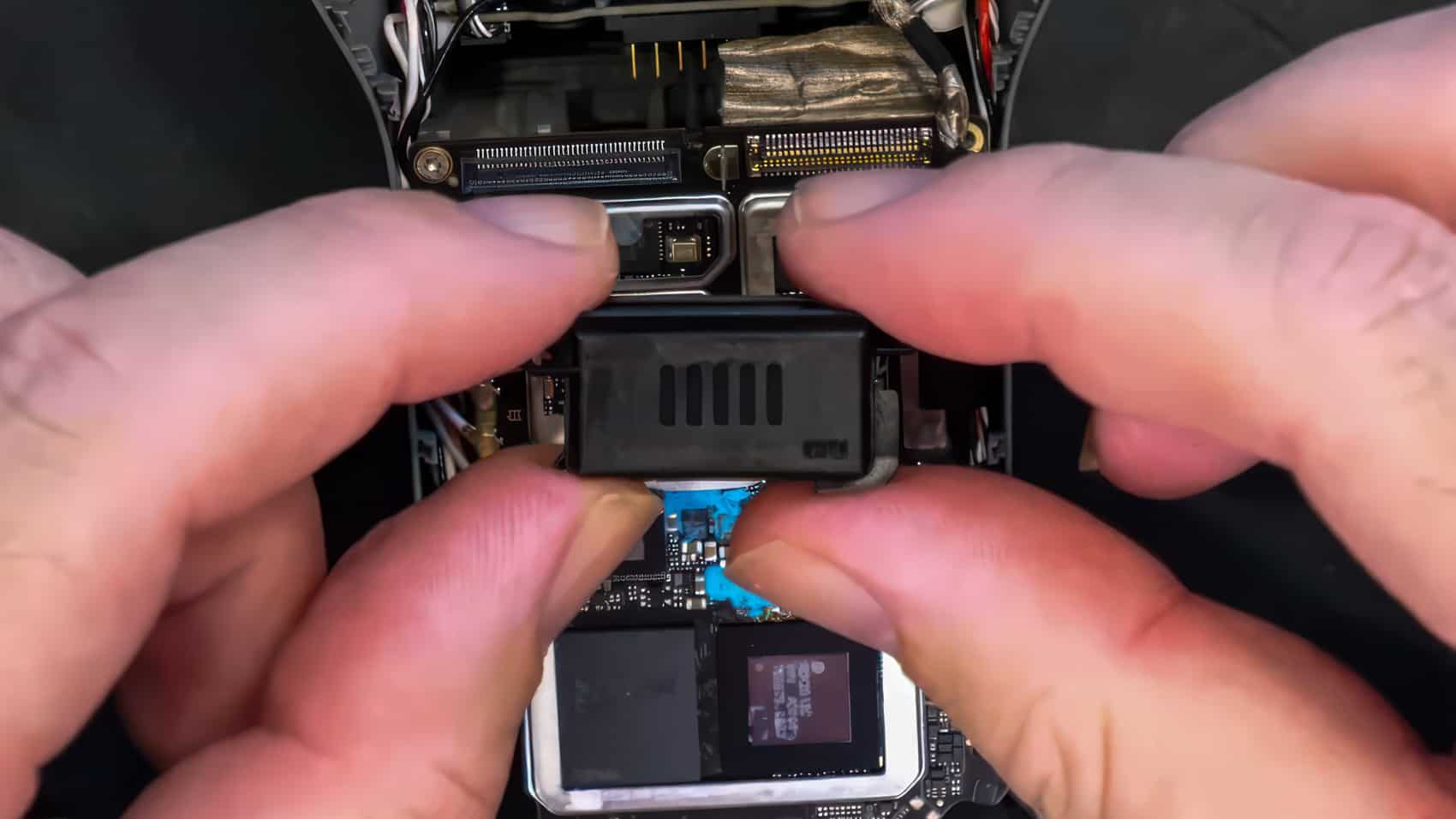 Hands lift the black speaker unit out of its bay on the mainboard.
