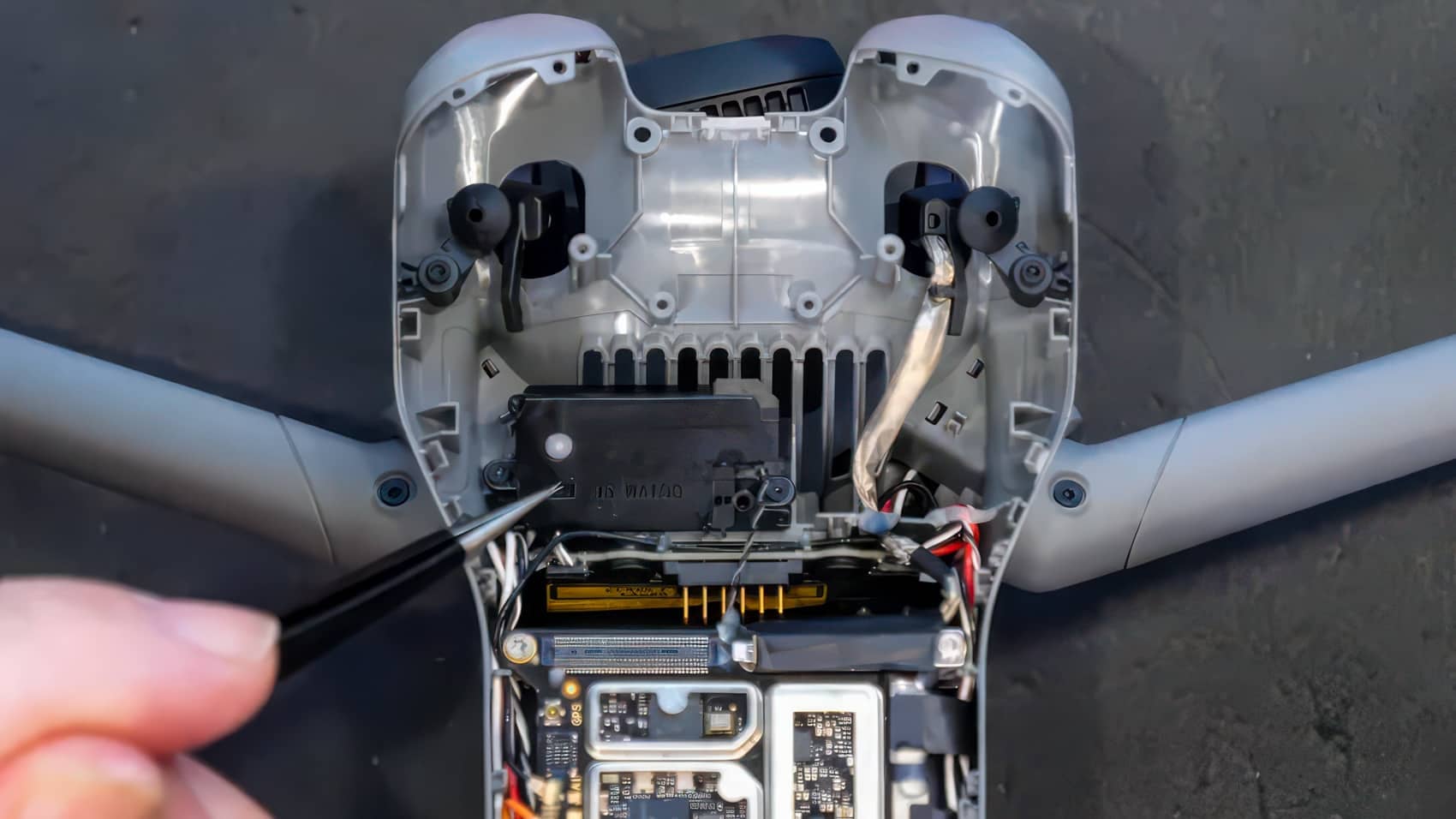 Tweezers point to the speaker seated beside the heat sink inside the airframe.
