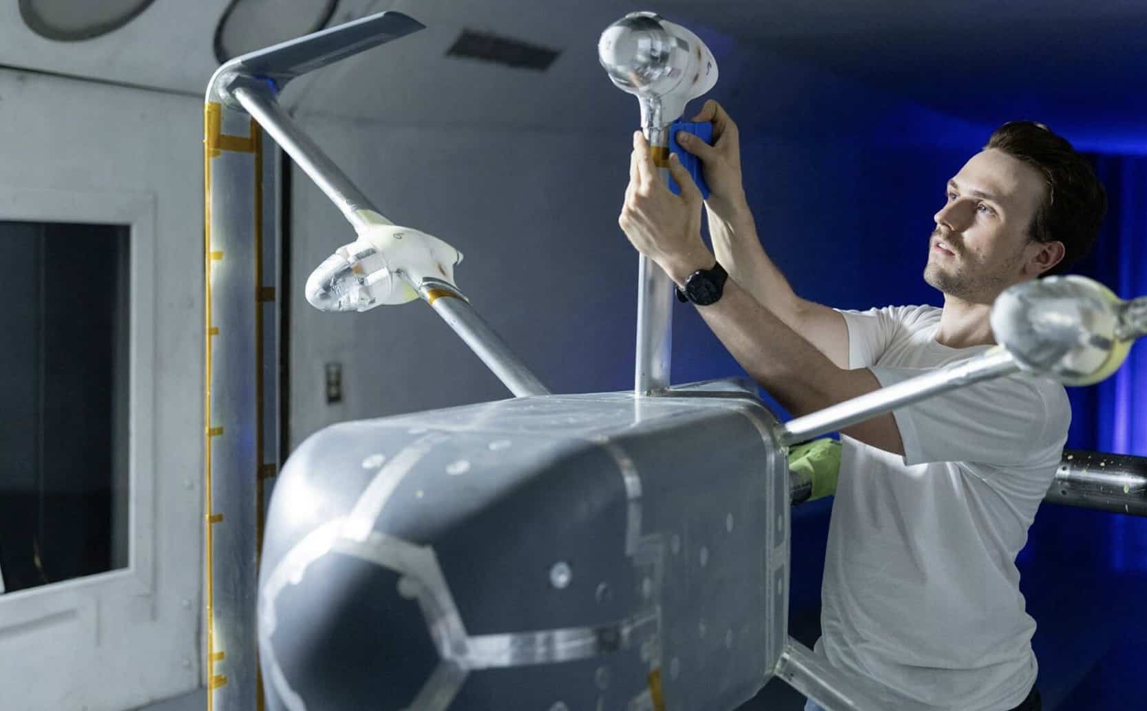 Technician fitting a rotor arm to a delivery drone airframe in a lab.