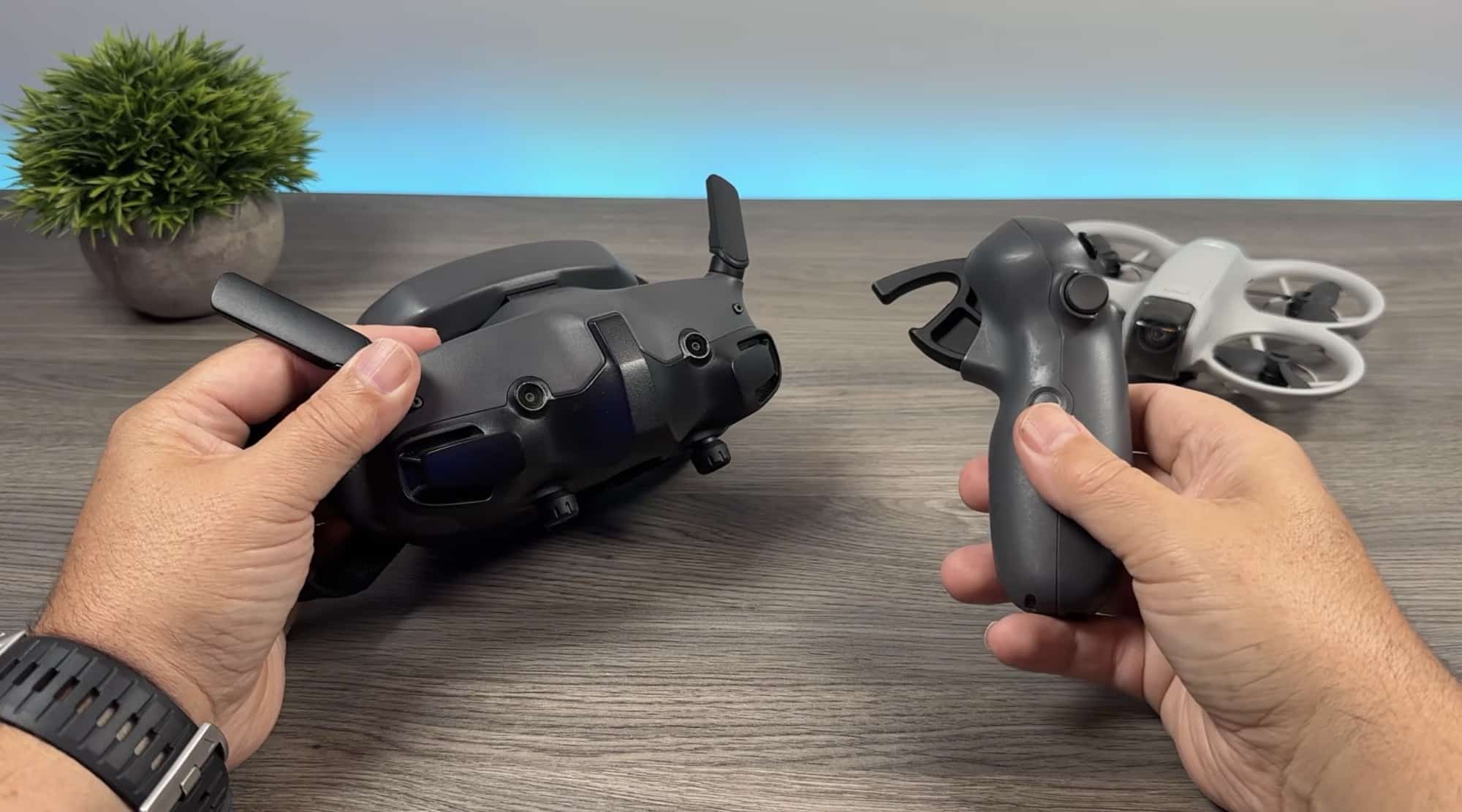Hands hold FPV goggles and a motion controller beside the Neo on a desk.