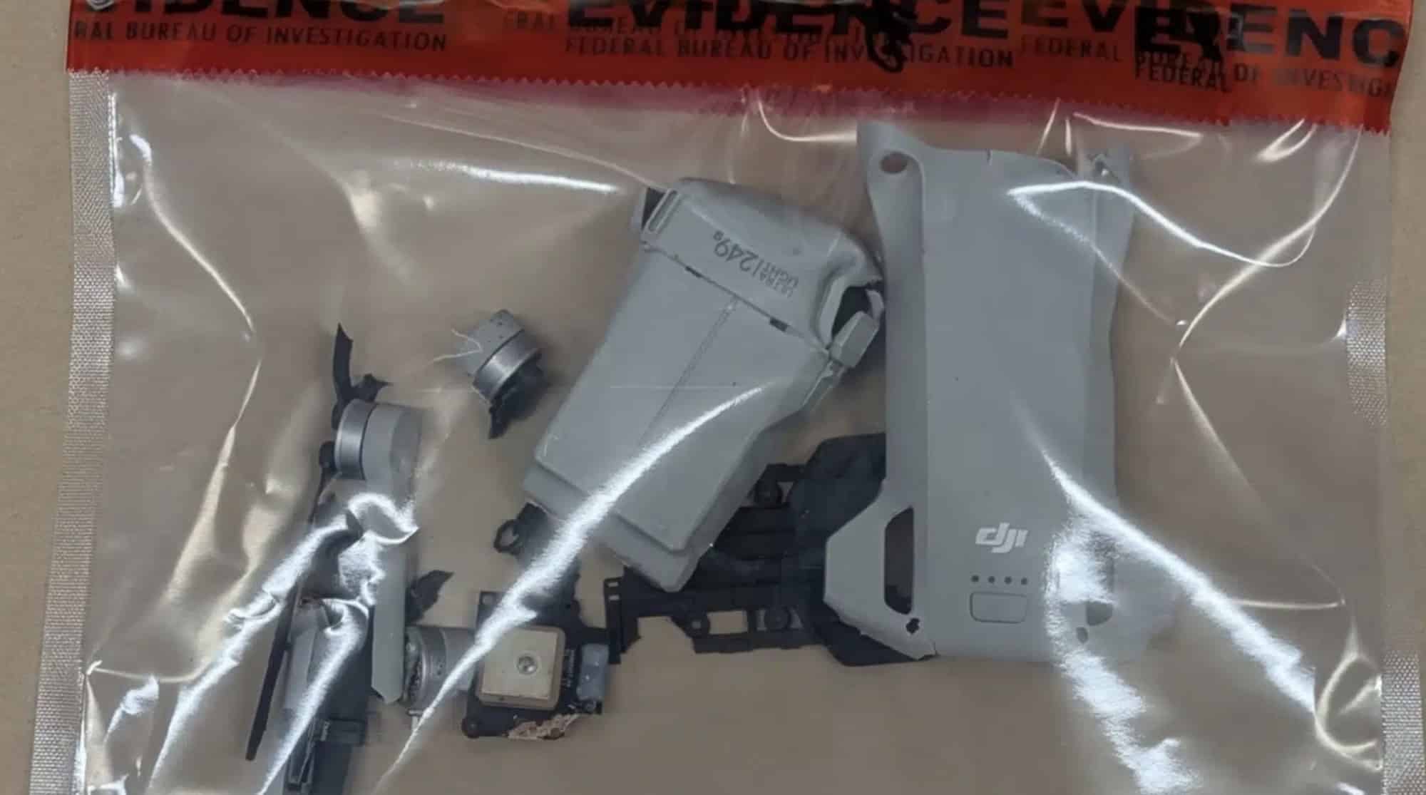 Recovered drone parts sealed inside a clear evidence bag against a red backdrop.